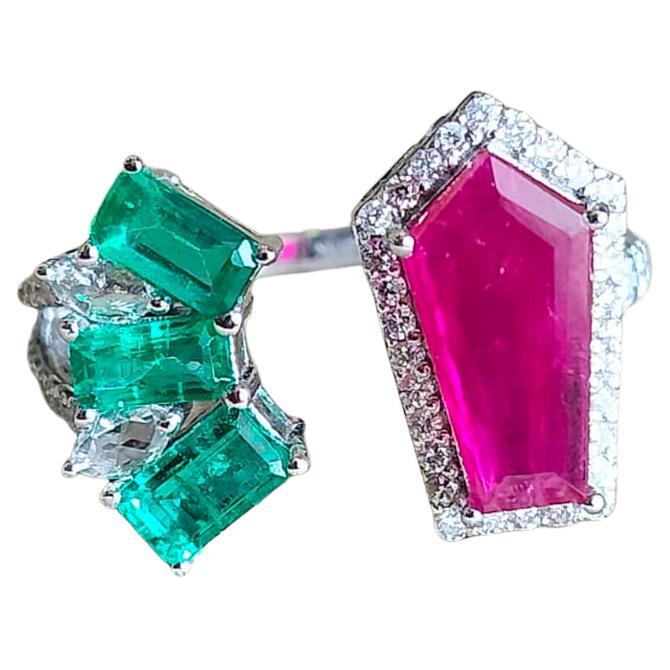 A classic Modern style Ruby & Emerald Engagement/ Cocktail ring set in 18K Gold & Diamonds. The weight of the Ruby is 1.41 carats. The shield shaped Ruby is completely natural, without any treatment and is of Mozambique origin. The weight of the