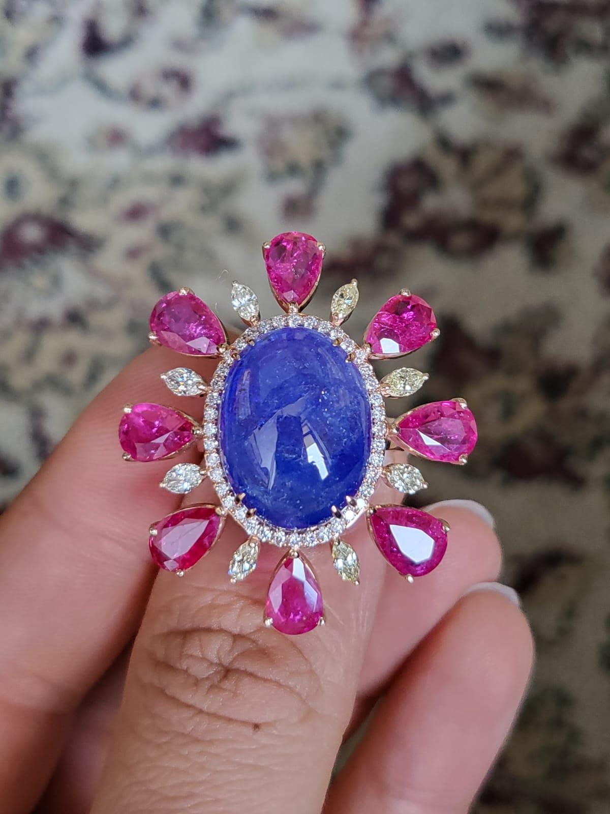 A very gorgeous, one of a kind and modern, Tanzanite & Ruby Cocktail Ring set in 18K Rose Gold & Diamonds. The weight of the Tanzanite Cabochon is 15.48 carats. The Tanzanite is responsibly sourced from Tanzania. The weigh of the pear shaped Rubies