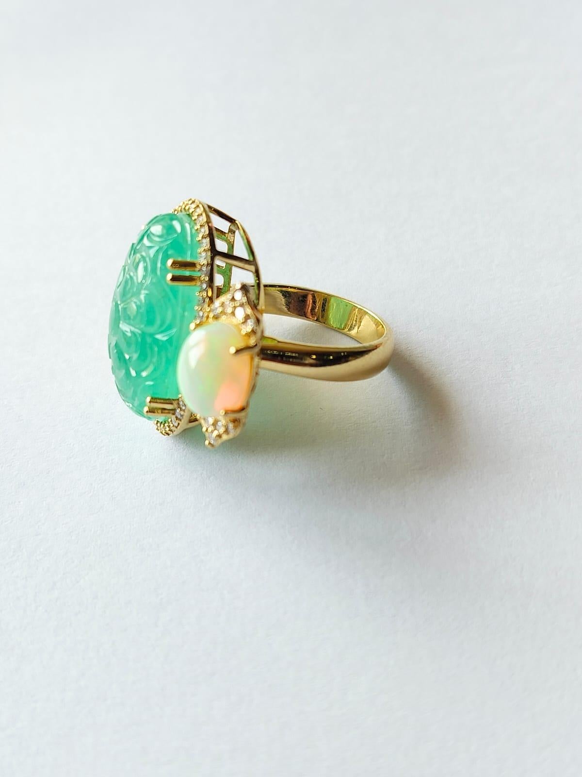 A very gorgeous and beautiful, Art Deco style Emerald and Opal Ring set in 18K Gold & Diamonds. The weight of the Emerald is 18.22 carats. The carved Emerald is of Russian origin and is completely natural, without any treatment. The weight of Opal