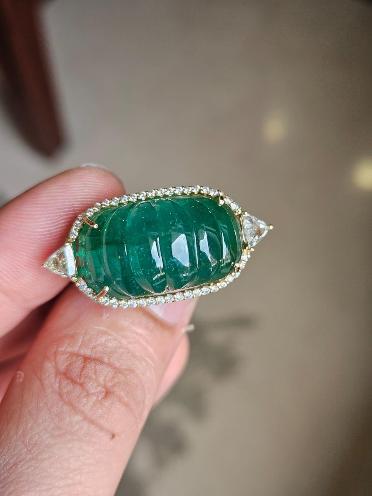 A very gorgeous and beautiful, Art deco style, Emerald Cocktail Ring set in 18K Yellow Gold & Diamonds. The weight of the carved Emerald is 28.47 carats. The Emerald is completely natural, without any treatment and is of Zambian origin. The combined