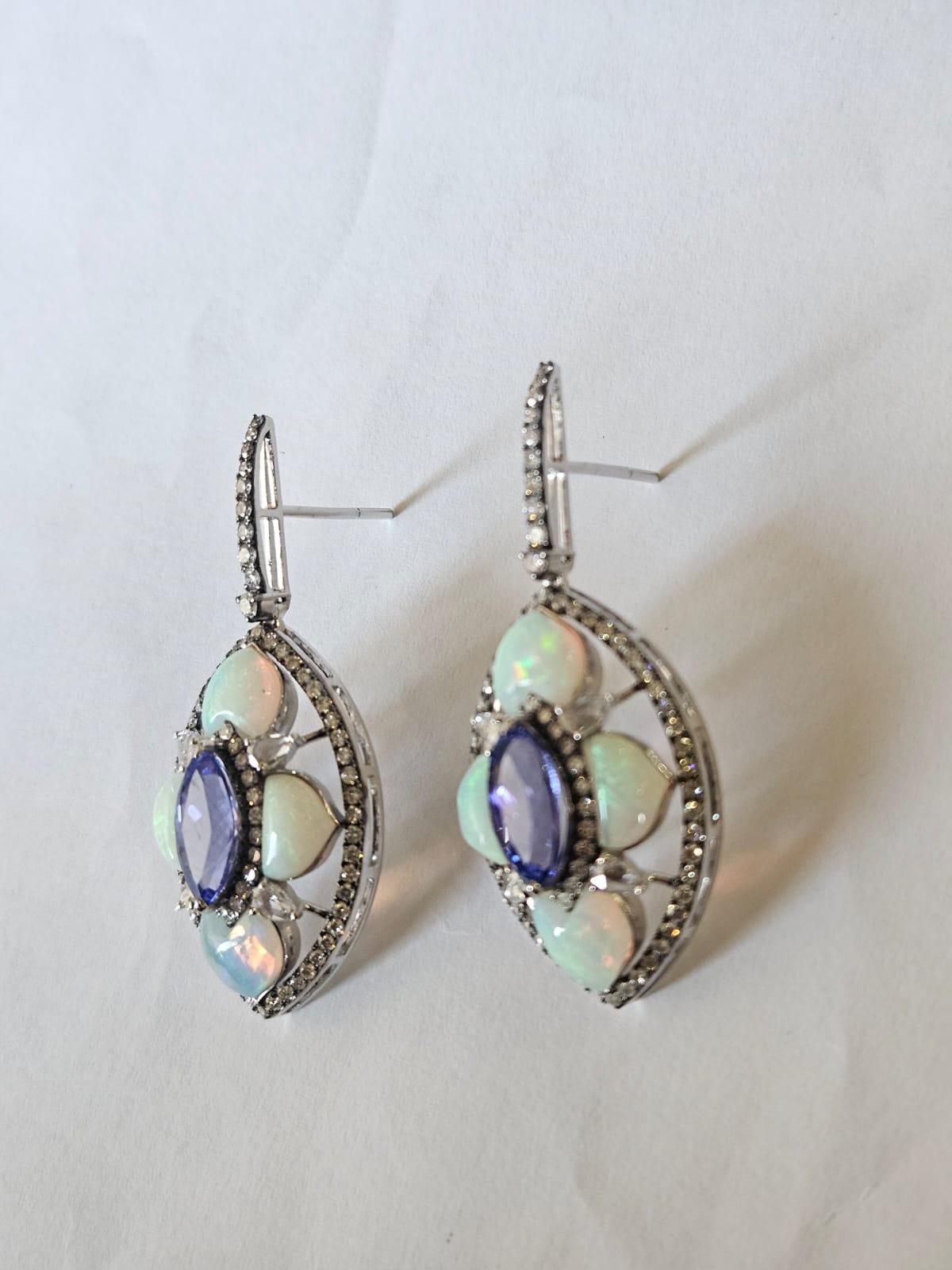 Bellissimi orecchini pendenti in stile moderno con tanzanite e opale, incastonati in oro bianco 18 carati e diamanti naturali. Il peso delle tanzaniti è di 3,35 carati. Le tanzaniti provengono in modo responsabile dalla Tanzania. Il peso dell'opale