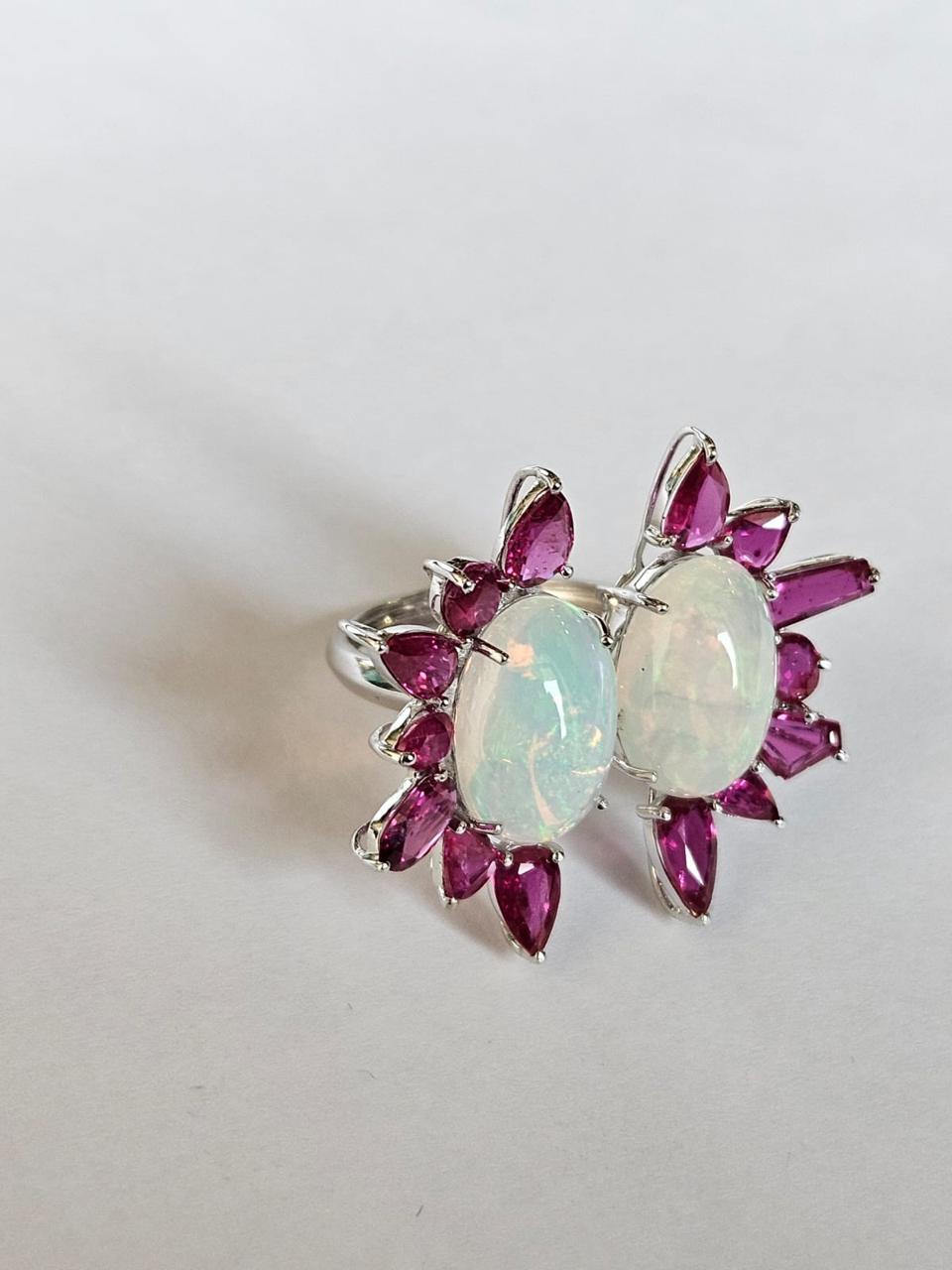 Un Anillo de Cóctel de Ópalo y Rubí muy bonito y especial, engastado en Oro Blanco de 18 quilates y Diamantes. El peso de los Ópalos es de 6,30 quilates. Los ópalos son de origen etíope. El peso del rubí es de 5,45 quilates. Los Rubíes son