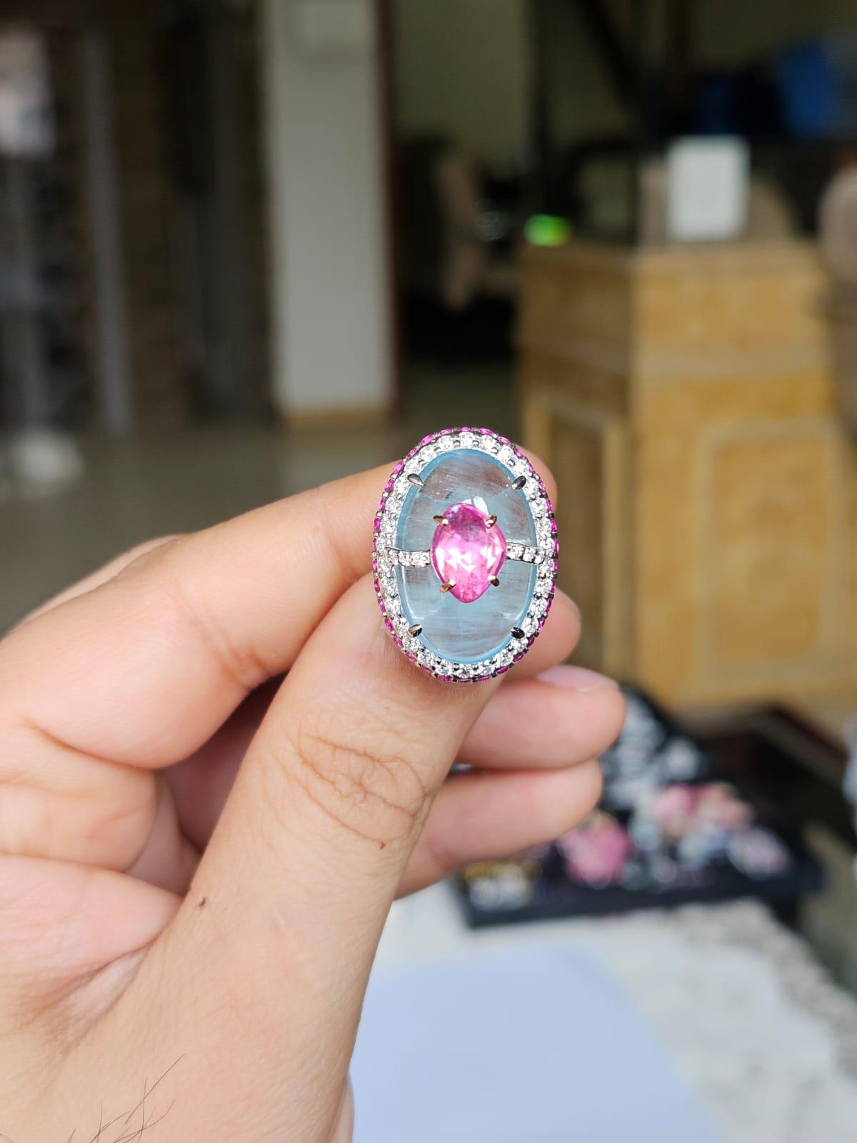 Une très belle bague d'aigue-marine et de saphirs roses en or blanc 18 carats et diamants naturels de style moderne. Le poids du cabochon d'aigue-marine est de 12,54 carats. Le poids combiné des saphirs roses est de 2.70 carats. Les saphirs roses