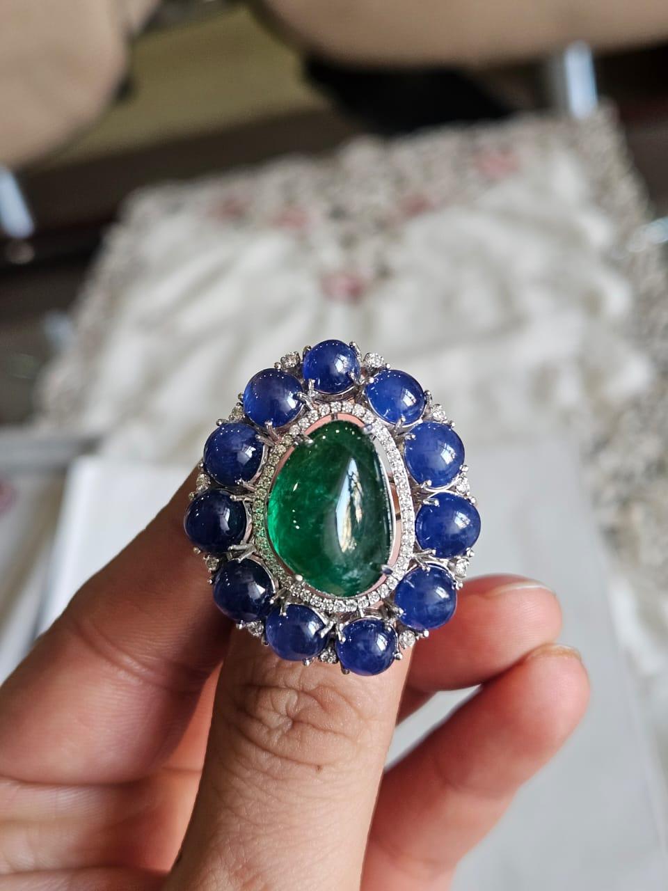 Très belle bague de style moderne en or blanc 18 carats, sertie de saphirs bleus et d'émeraudes et de diamants naturels. Le poids des saphirs bleus est de 19.80 carats. Les saphirs bleus sont entièrement naturels, sans aucun traitement, et sont