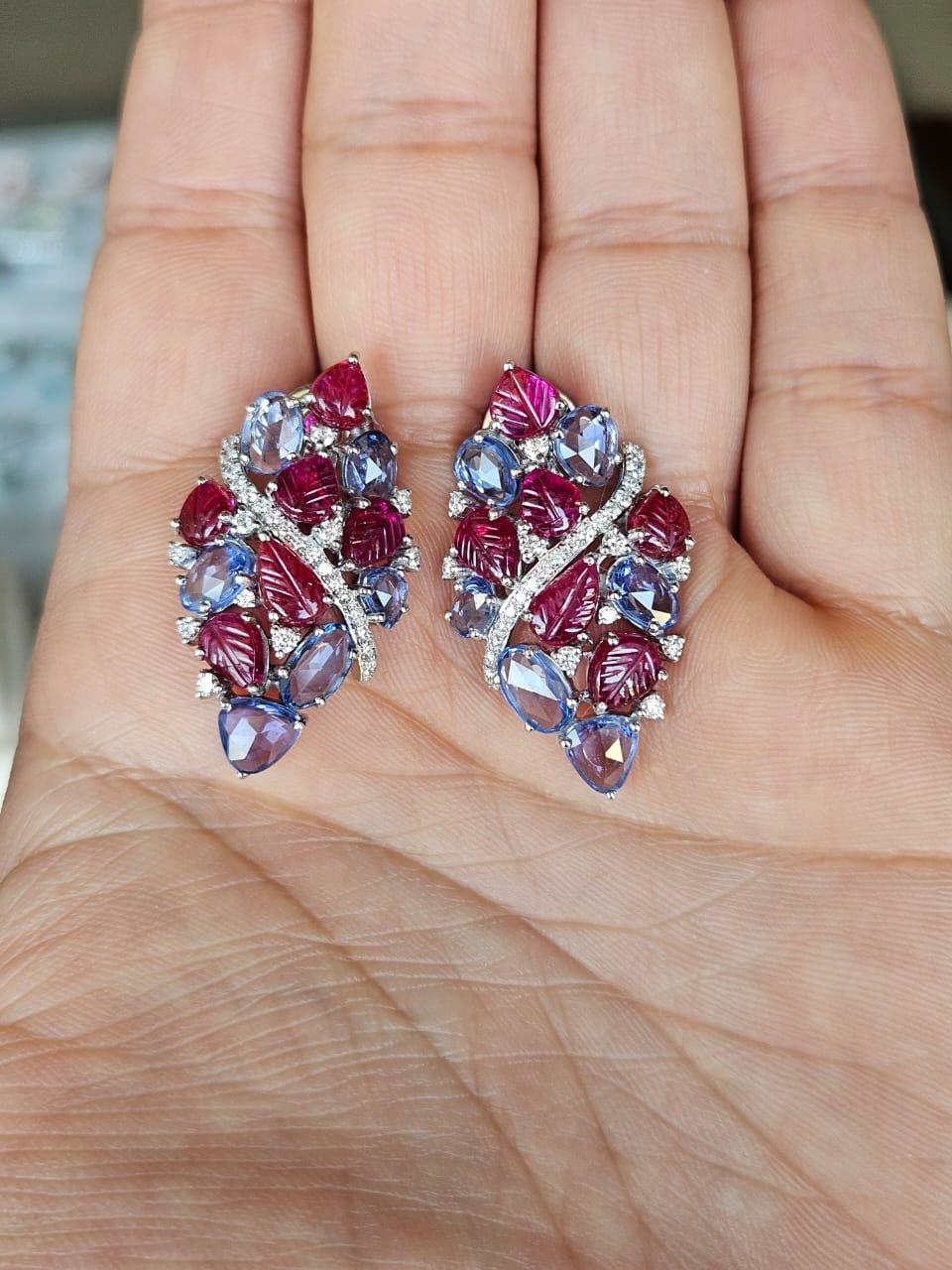 Ein wunderschöner, blauer Saphir & Rubin Ohrstecker aus 18 Karat Weißgold und natürlichen Diamanten. Das Gewicht der blauen Saphire beträgt 6.54 Karat. Die blauen Saphire stammen aus Ceylon (Sri Lanka). Das Gewicht der geschnitzten Rubine beträgt