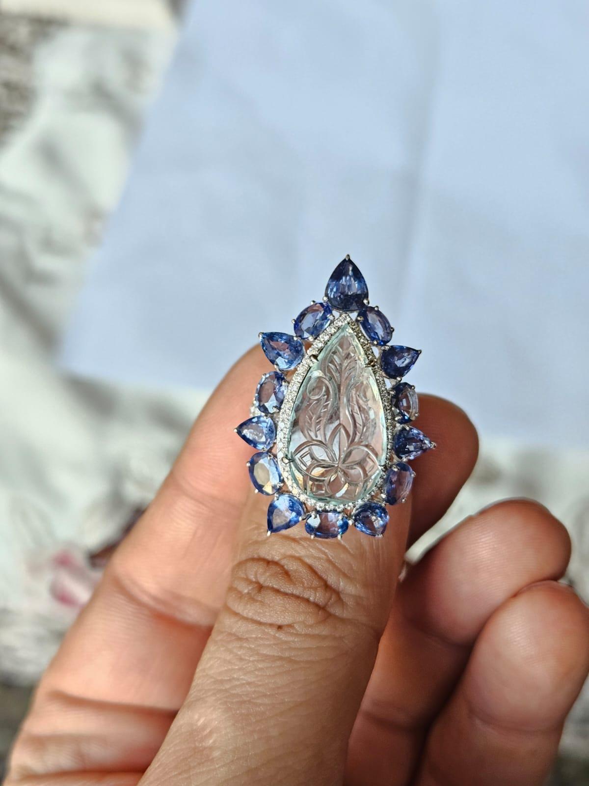A very gorgeous and beautiful, Aquamarine & Blue Sapphires Cocktail Ring set in 18K White Gold & natural Diamonds. The weight of the carved Aquamarine is 6.86 carats. The Aquamarine is responsibly sourced, cut, polished and hand-carved in our very