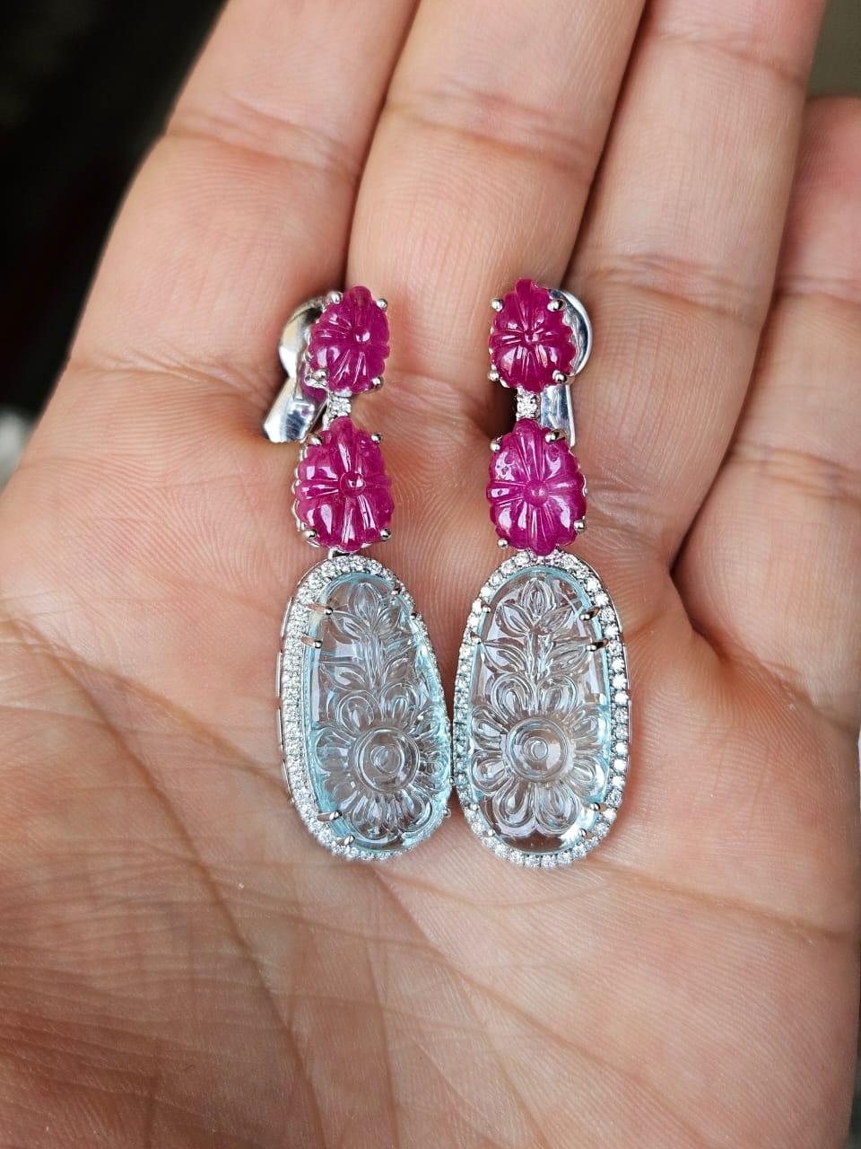 Très belles boucles d'oreilles de style moderne en or blanc 18 carats et diamants naturels, composées de rubis et d'aigue-marine. Le poids des aigues-marines sculptées est de 18.70 carats. Le poids des rubis sculptés est de 9.63 carats. Les rubis