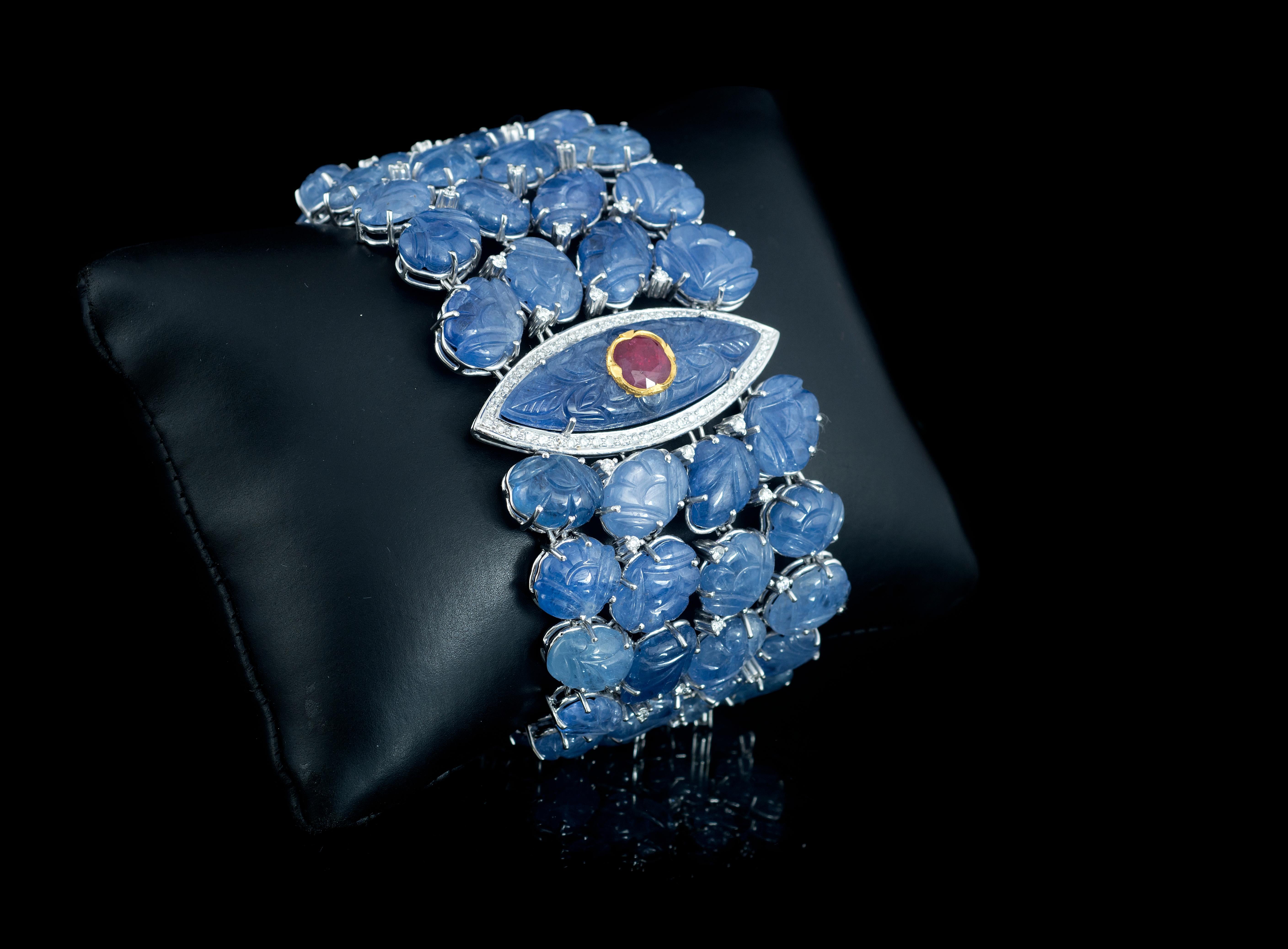 A one of a kind, natural, Burma Blue Sapphire, Ruby and Diamonds bracelet set in 18K white gold. The centre carving of Blue Sapphire is engraved with a natural Ruby using Kundan (24K yellow gold). The weight of the centre Blue Sapphire carving and