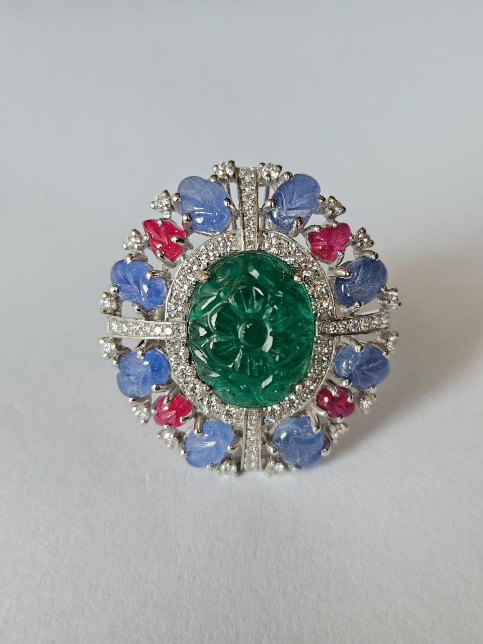 A very gorgeous and beautiful, one of a kind, Emerald, Blue Sapphires & Rubies Cocktail Ring set in 18K White Gold & natural Diamonds. The carved Emerald is completely natural, without any treatment and is of Zambian origin. The carved Blue