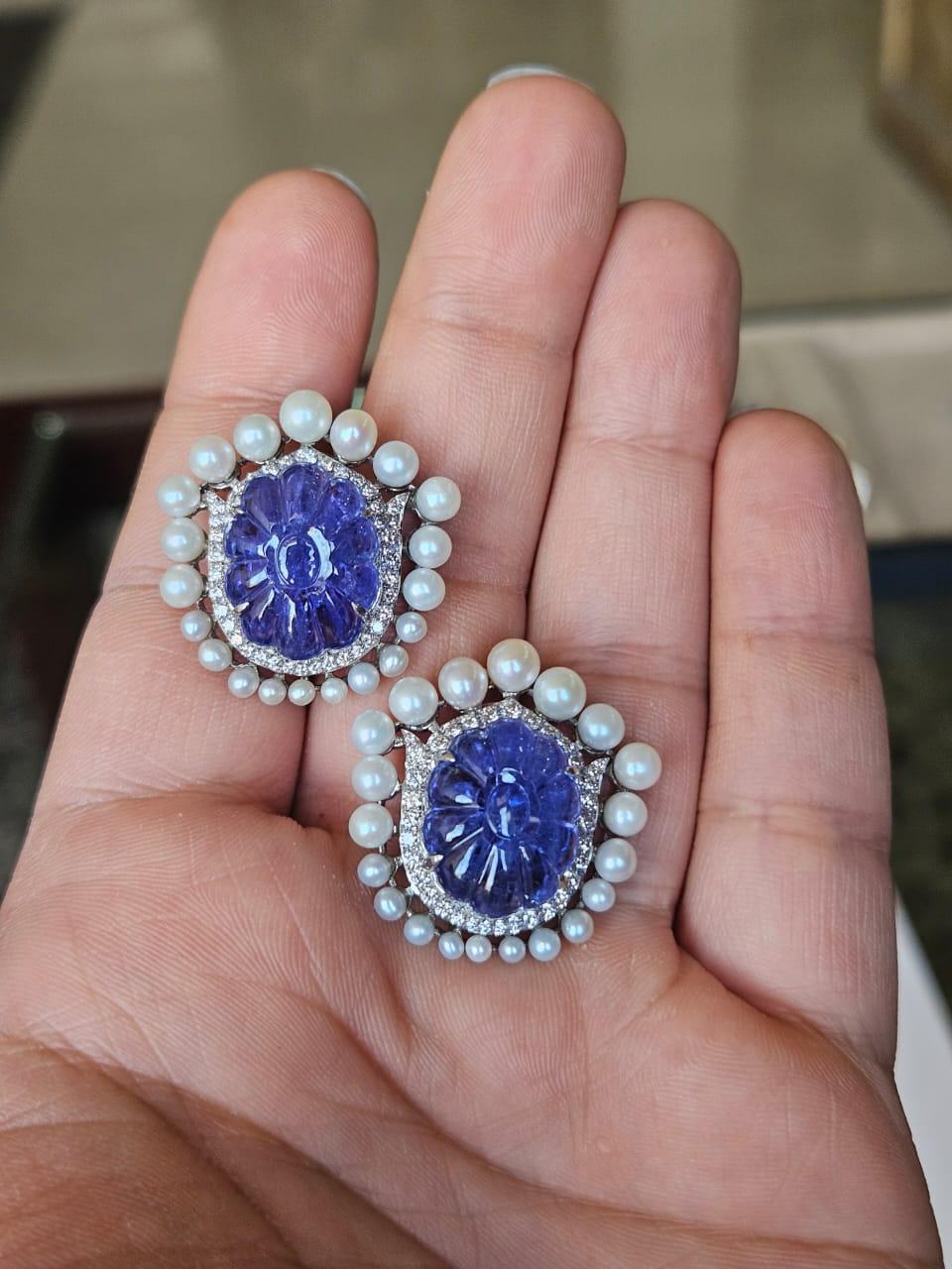 Magnifiques boucles d'oreilles de style moderne en or blanc 18 carats et diamants naturels, composées de Tanzanites et de perles d'eau douce. Le poids des tanzanites est de 22.60 carats. Les tanzanites sculptées proviennent de Tanzanie et sont