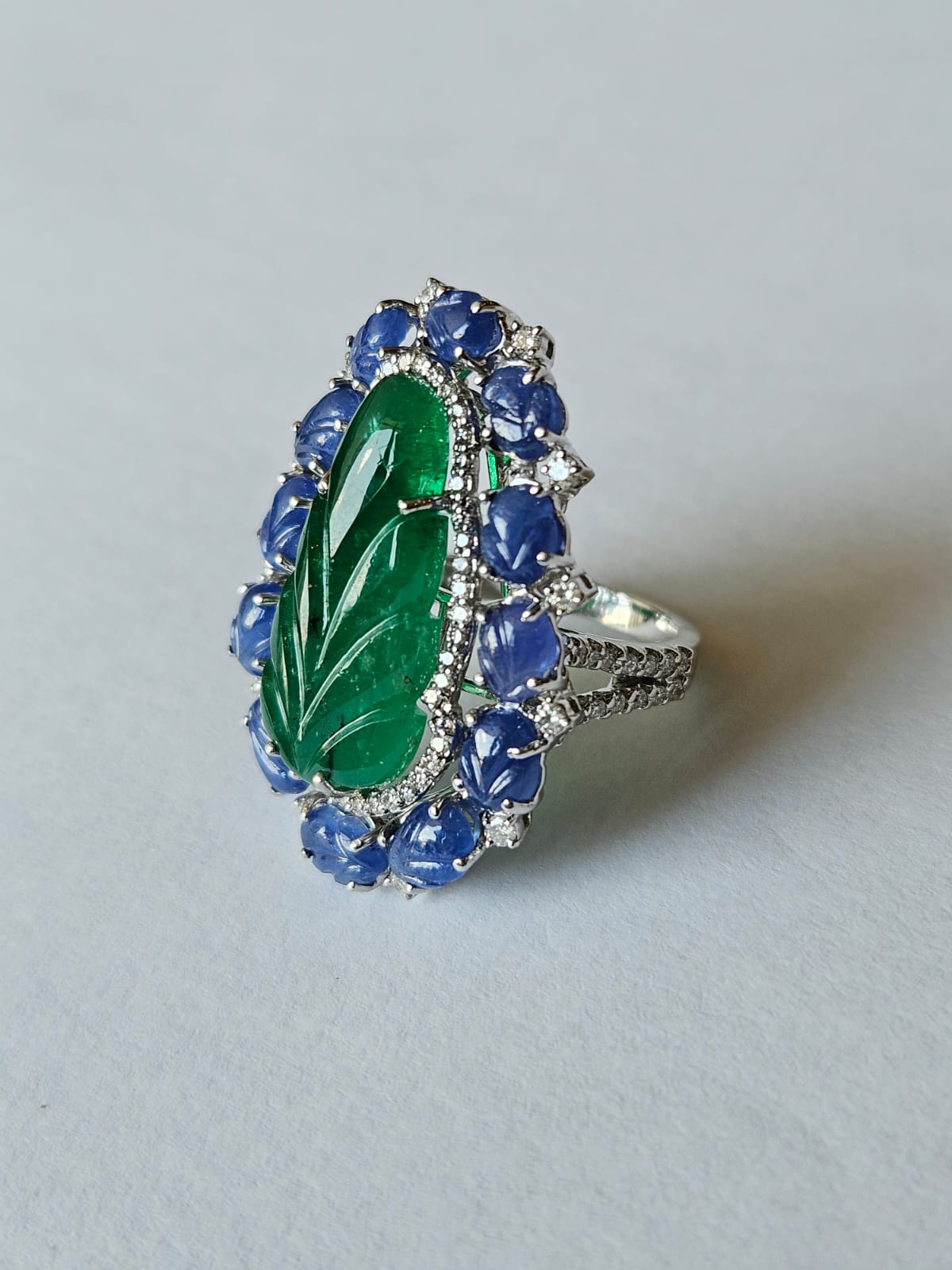 A very beautiful & gorgeous, Art deco style, Emerald & Blue Sapphire Cocktail Ring set in 18K White Gold & Diamonds. The weight of the carved Emerald is 9.83 carats. The Emerald is completely natural, without any treatment and is of Zambian origin.