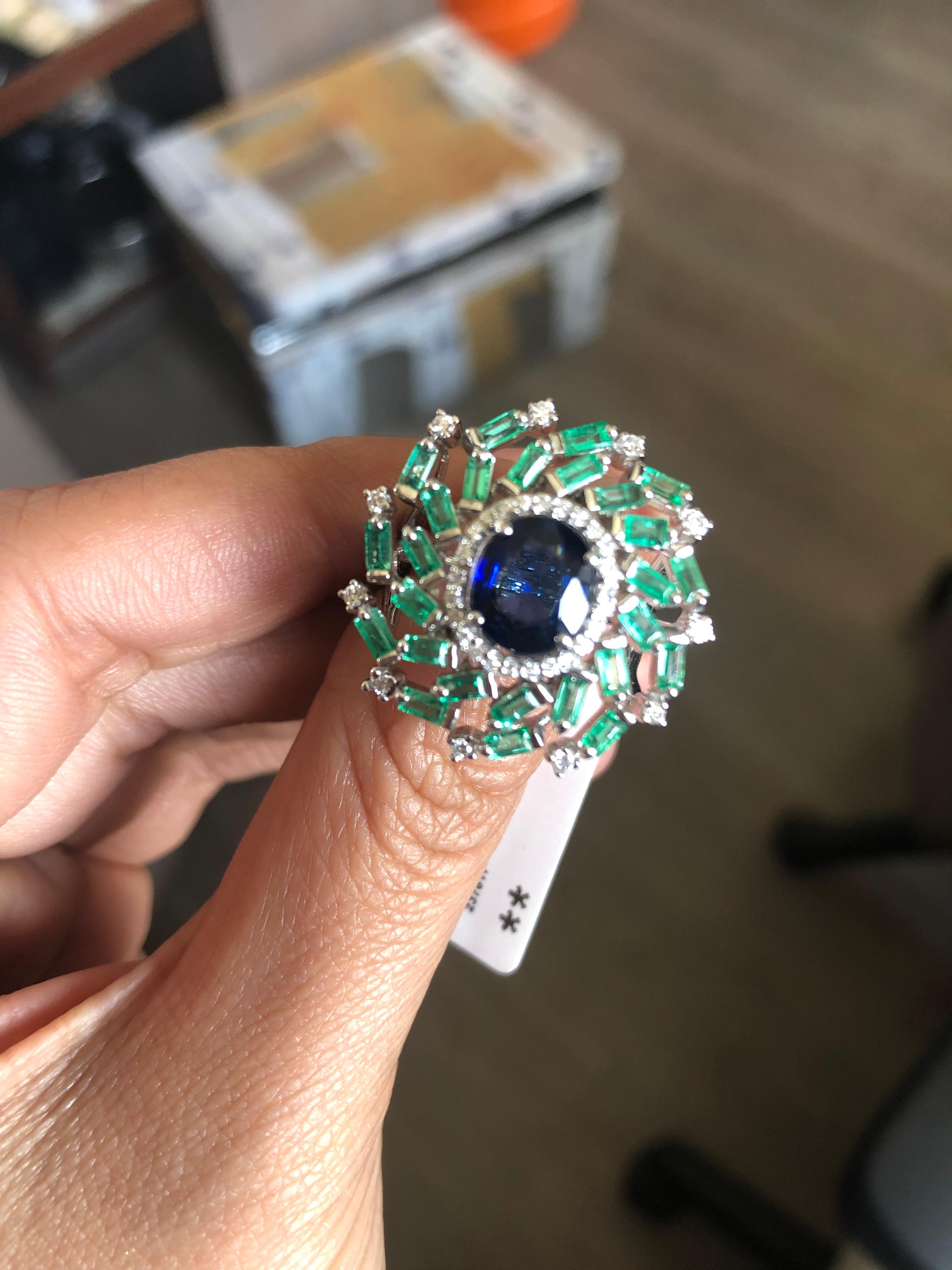 An off - beat Blue Sapphire & Emerald Cocktail Ring set in 18K gold & Diamonds. The Blue Sapphire is from Sri Lanka, and weighs 1.77 carats. The Blue Sapphire is from Sri Lanka. The weight of the Emeralds Baguettes is 1.22 carats. The Emeralds are