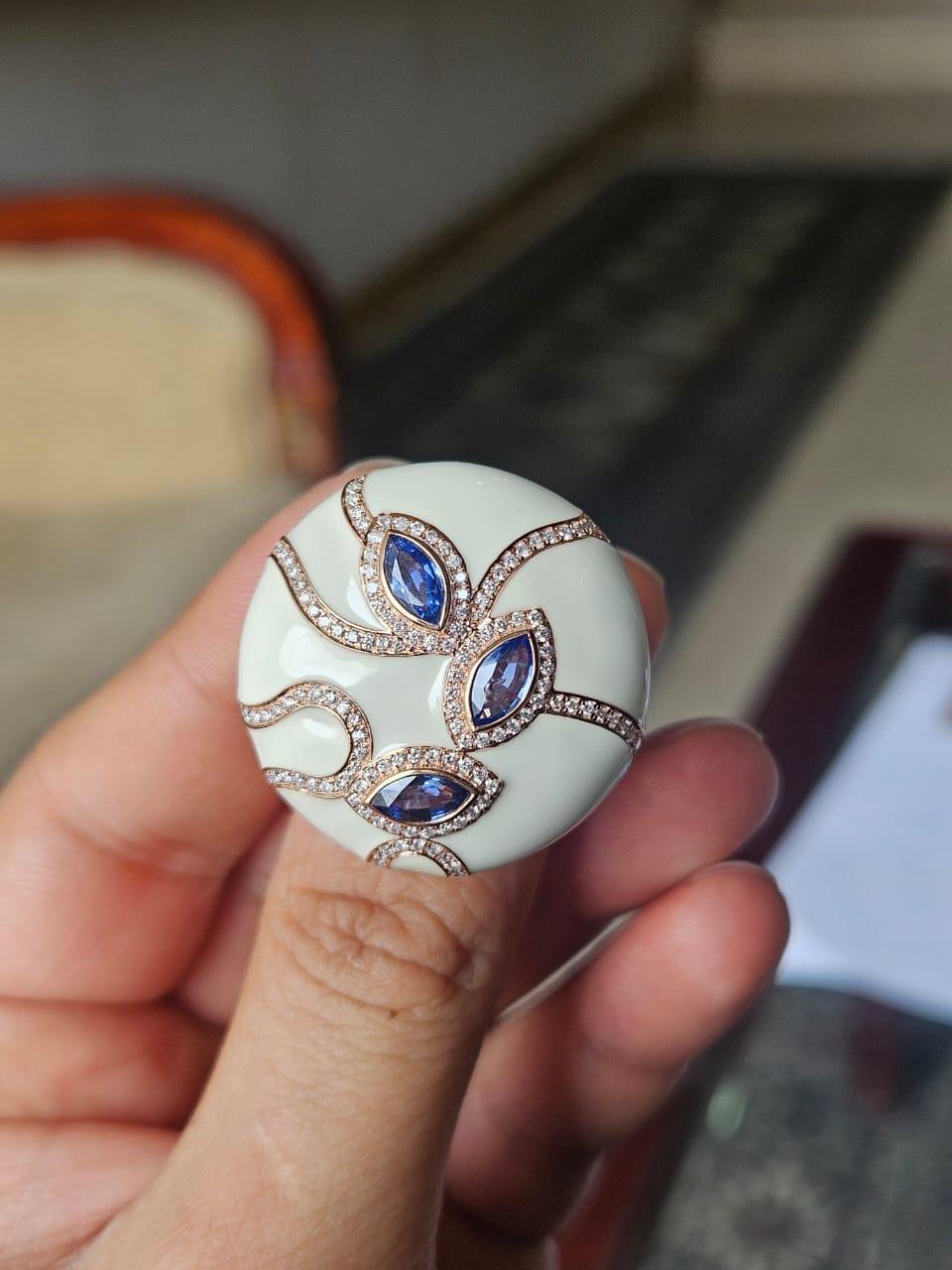 Ein sehr schöner, moderner Cocktailring mit blauen Saphiren und weißer Emaille in 18 Karat Gold und natürlichen Diamanten. Das Gewicht der blauen Saphire beträgt 1.46 Karat. Die blauen Saphire stammen aus Ceylon (Sri Lanka). Das Gewicht der