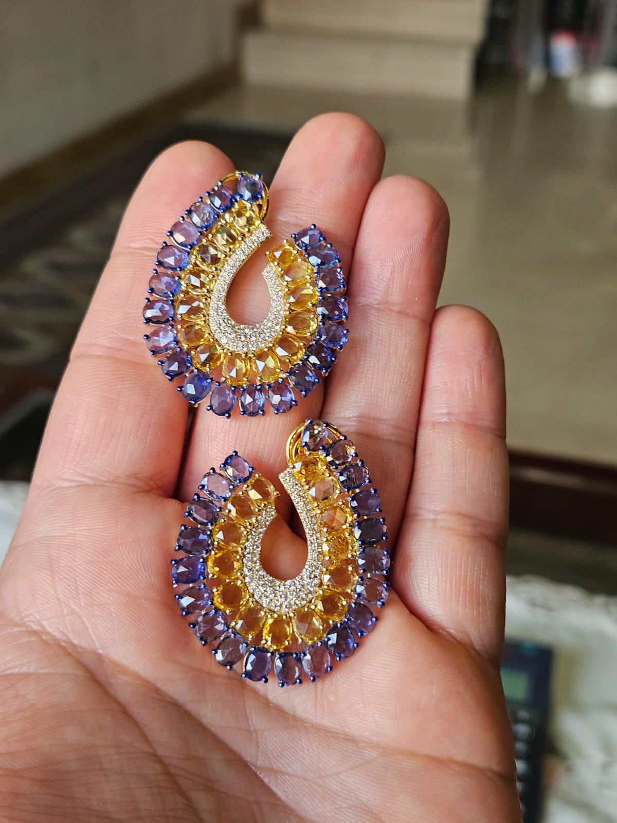 Un bellissimo orecchino a cerchio in stile moderno con zaffiri blu e zaffiri gialli, incastonato in oro 18 carati e diamanti naturali. Il peso combinato degli zaffiri blu e gialli è di 23,58 carati. Gli zaffiri blu e gialli sono di Ceylon (Sri