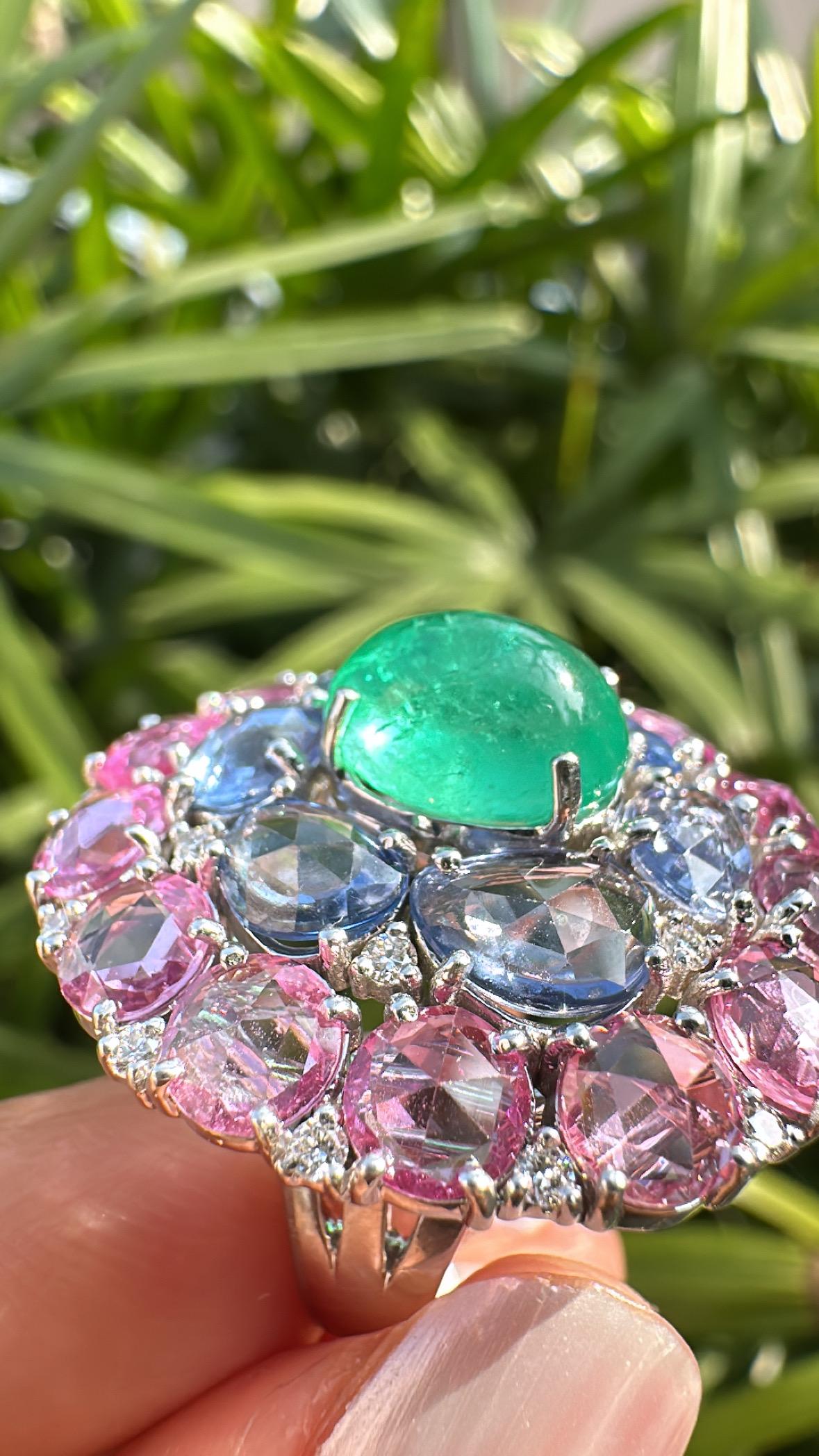 Ein wunderschöner Cocktailring aus Smaragd, blauem und rosa Saphir in 18 Karat Weißgold und natürlichen Diamanten. Das Gewicht des Smaragd-Cabochons beträgt 3.58 Karat. Der Smaragd ist völlig natürlich, unbehandelt und stammt aus Kolumbien. Das
