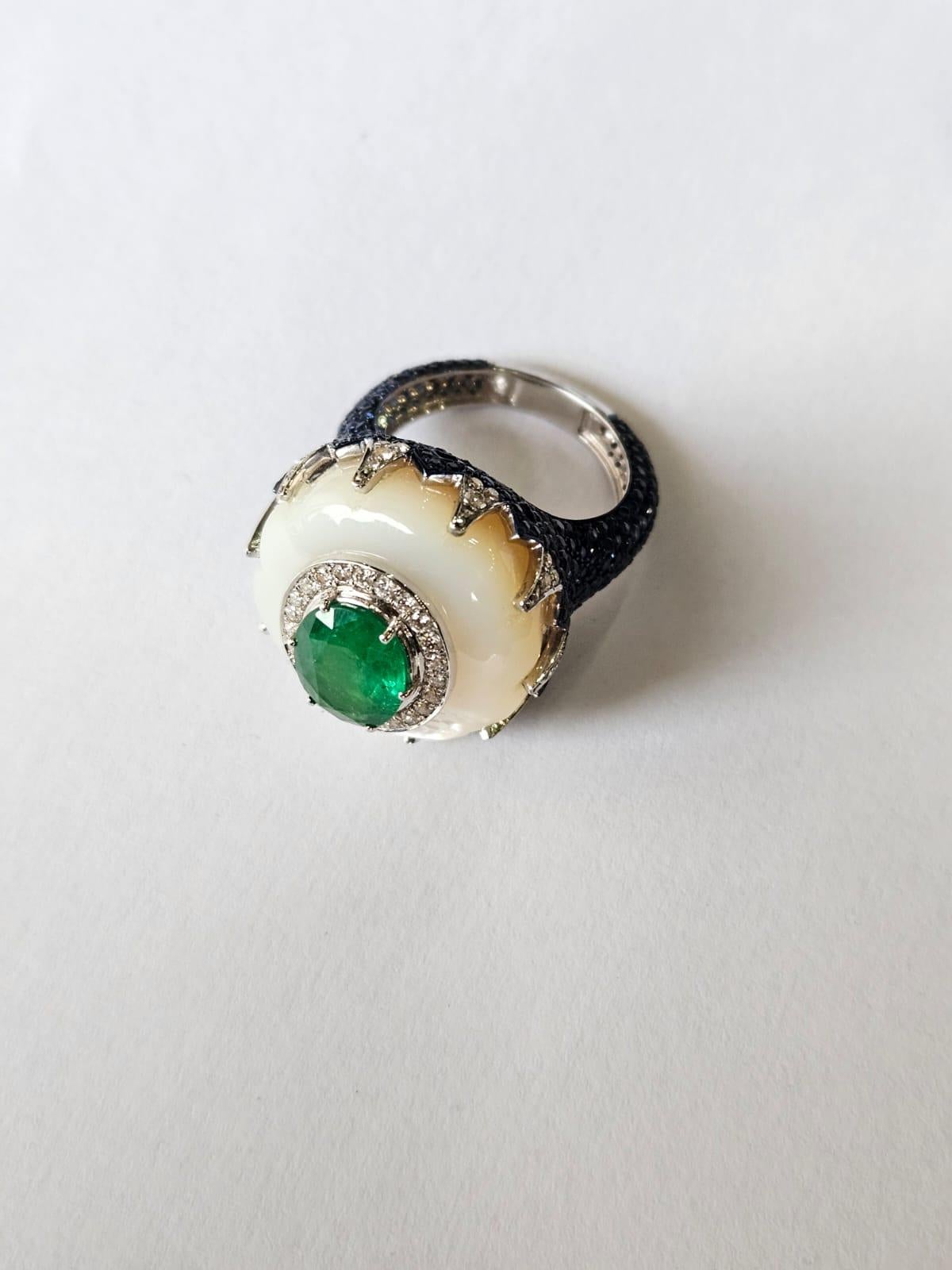 A very gorgeous and beautiful, one of a kind, Emerald, Mother of Pearl, Blue Sapphire Cocktail Dome Ring set in 18K White Gold & Diamonds. The weight of the Emerald is 2.30 carats. The Emerald is completely natural, without any treatment and is of