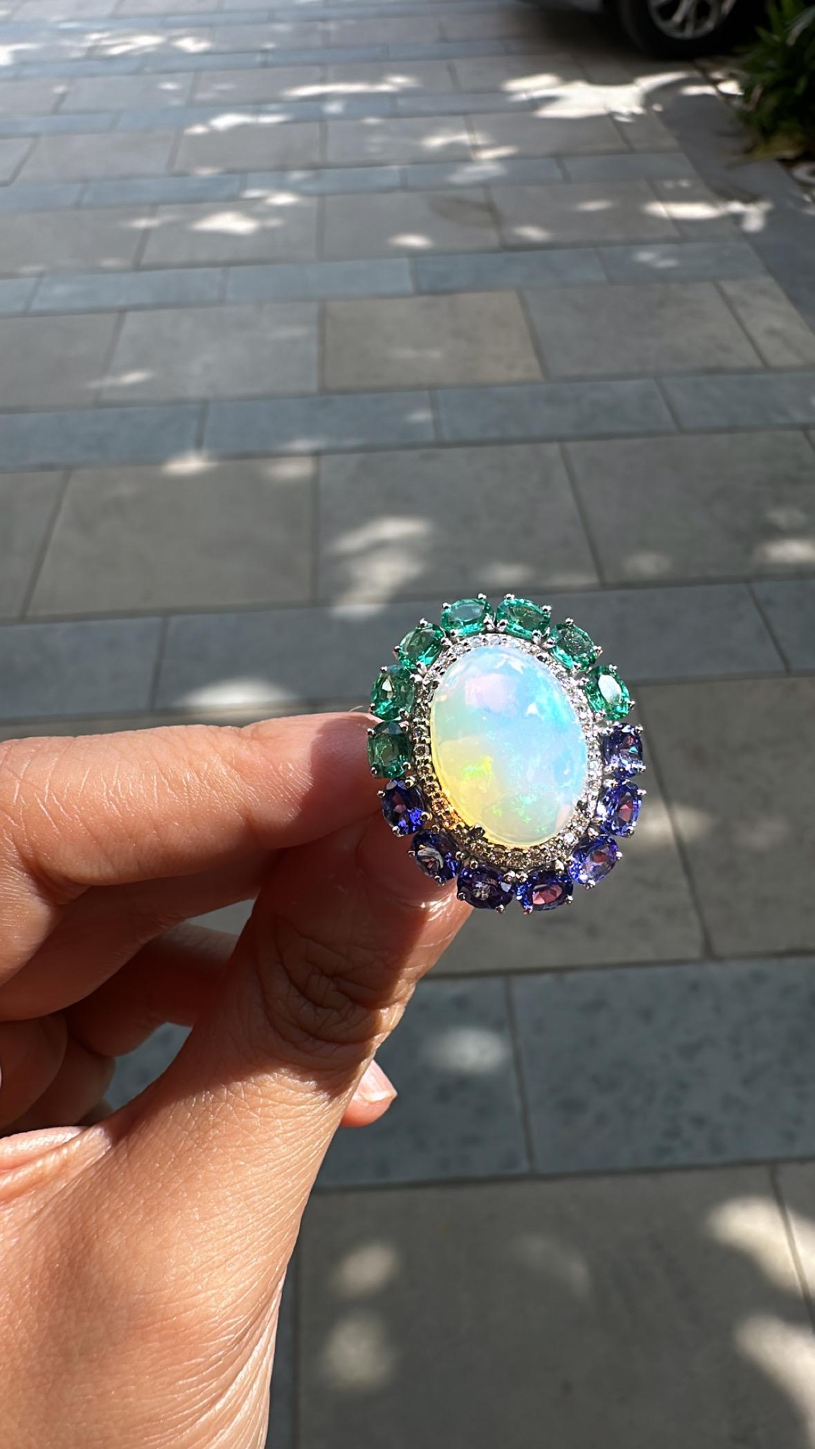 A very gorgeous and beautiful, modern style, Ethiopian Opal, Emeralds & Tanzanites Cocktail Ring set in 18K White Gold & natural Diamonds. The weight of the Ethiopian Opal is 9.51 carats. The weight of the Emeralds is 2.14 carats. The Emeralds are