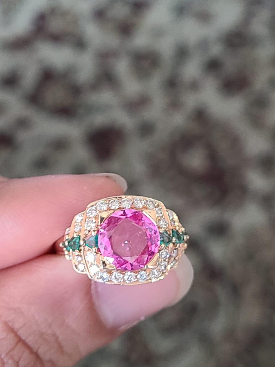 A very beautiful and dainty Pink Sapphire & Emerald Cocktail Ring set in 18K Gold and Diamonds. The weight of the Pink Sapphire is 2.19 carats. The Pink Sapphire is of Madagascar origin. The weight of the Emeralds is 0.28 carats. The weight of the