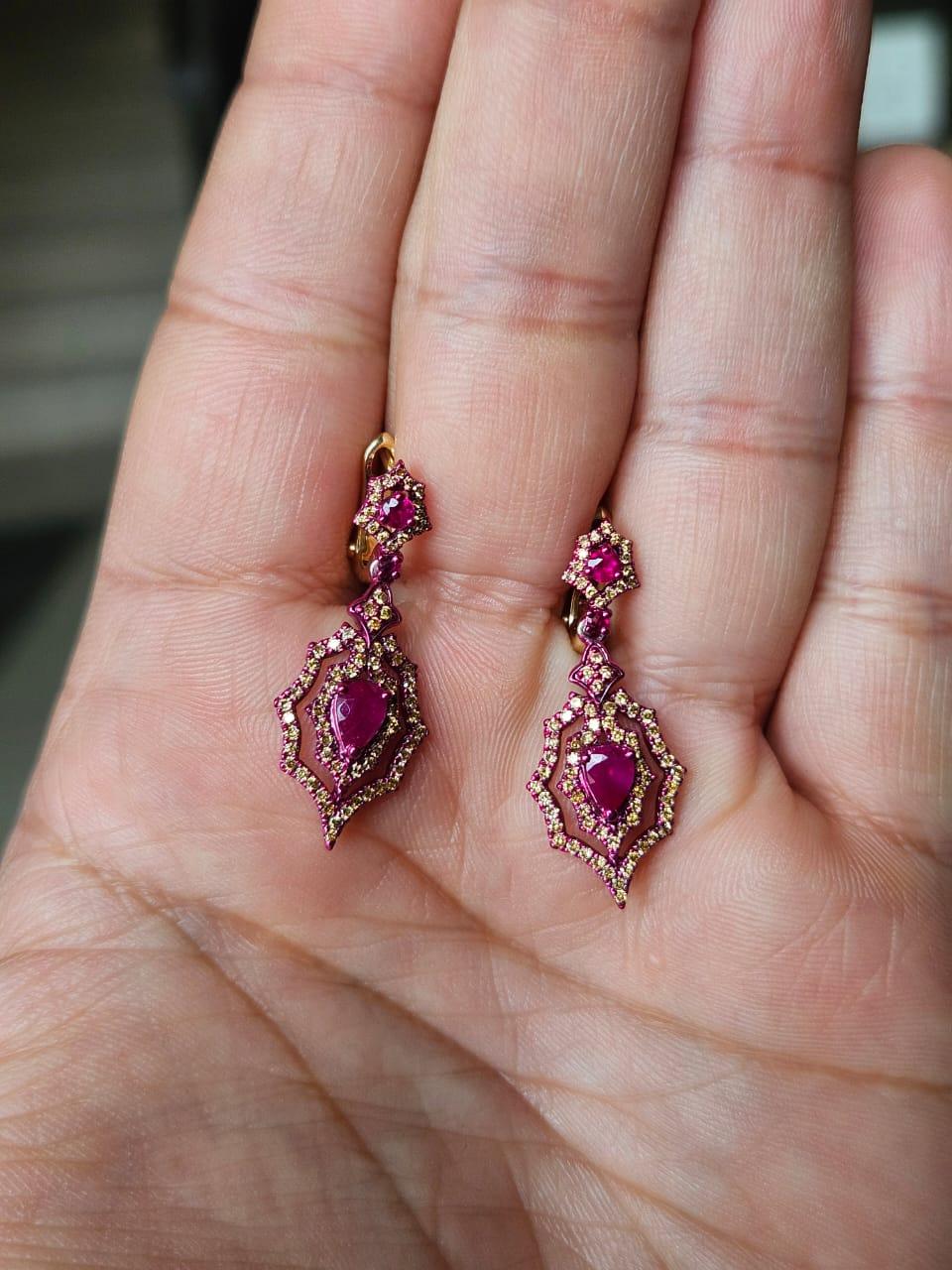 Orecchini pendenti in oro 18 carati con rodio rosso e diamanti naturali, molto speciali e moderni, unici nel loro genere. Il peso dei Rubini è di 0.96 carati. I rubini sono di origine mozambicana. Il peso dei diamanti è di 0,72 carati. Il peso netto