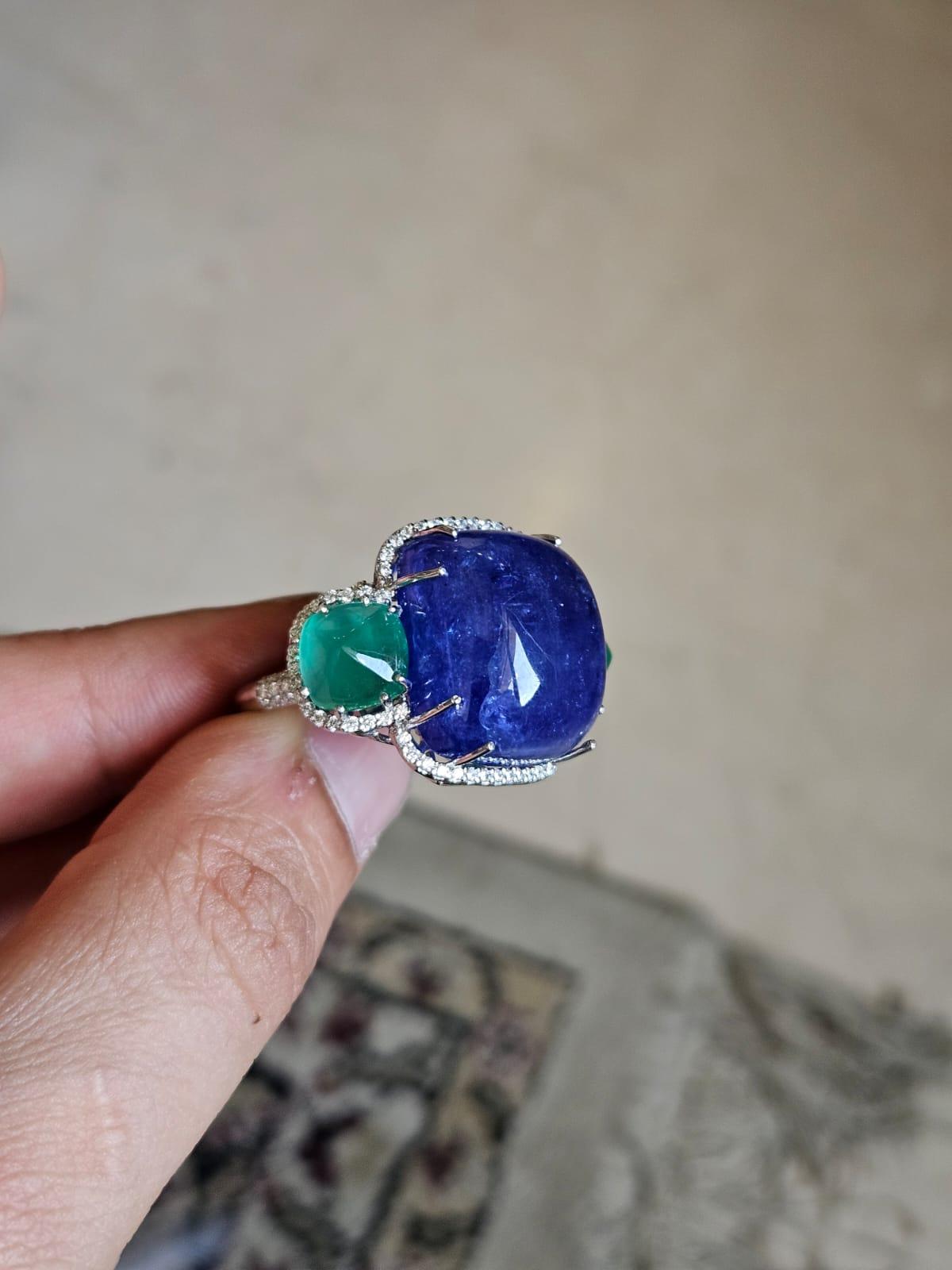 A very gorgeous and beautiful, one of a kind, Tanzanite & Emerald Cocktail Ring set in 18K White Gold & Diamonds. The weight of the Tanzanite Cabochon is 44.23 carats. The Tanzanite is responsibly sourced from Tanzania. The weight of the Emerald