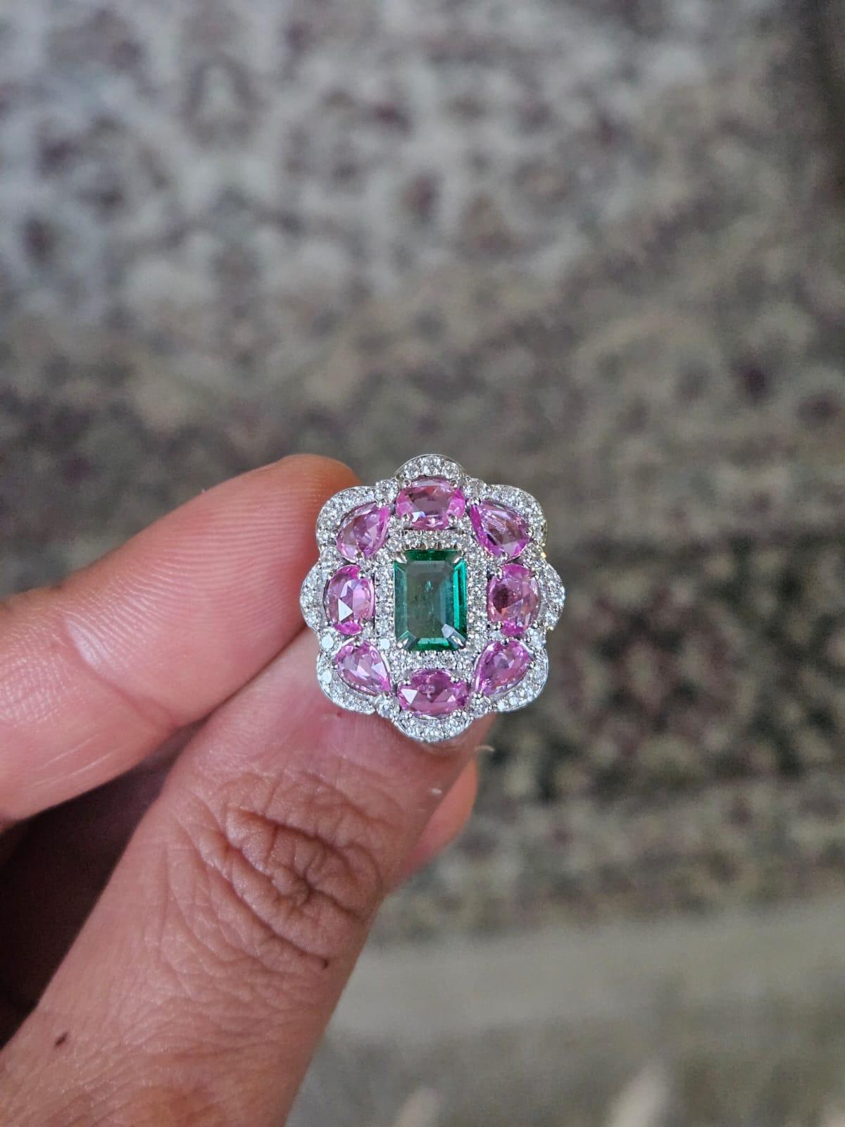 A very gorgeous and modern style, Emerald & Pink Sapphires Cocktail Ring set in 18K White Gold & natural Diamonds. The weight of the Emerald is 0.93 carats. The Emerald is completely natural, without any treatment and is of Zambian origin. The