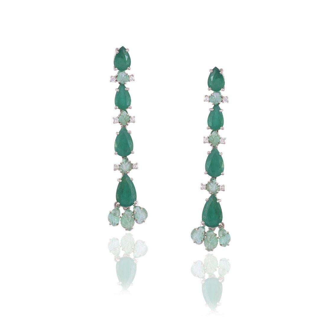 A very chic pair of Chandelier long earrings set in 18K White Gold & Diamonds. The earrings are made with a combination of Zambian pear shaped Emeralds & carved Russian Emeralds. The combined weight of the Emeralds is carats. The weight of the