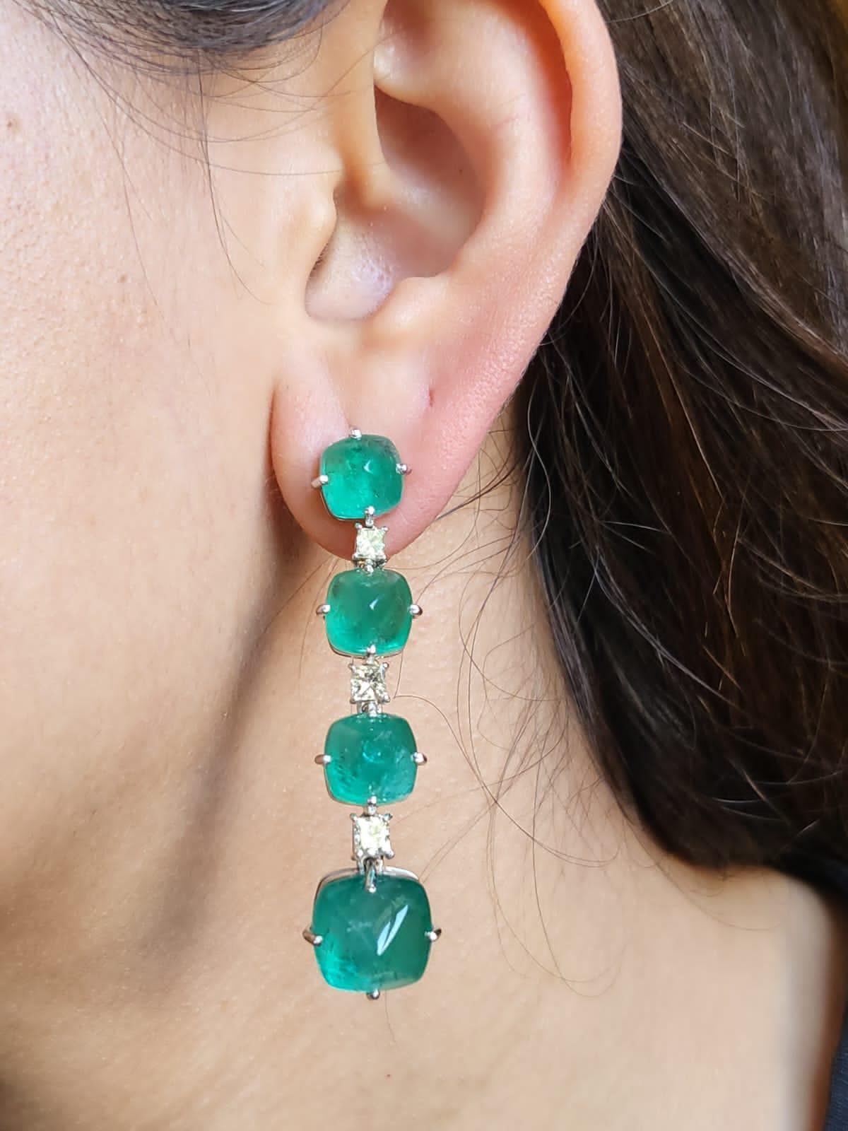 A very chic pair of Emerald Chandelier/ Dangle Earrings set in 18K White Gold & Diamonds. The weight of the Emerald sugarloafs is 31.99 carats. The Emerald Sugarloafs are completely natural, without any treatment and is of Zambian origin. The weight