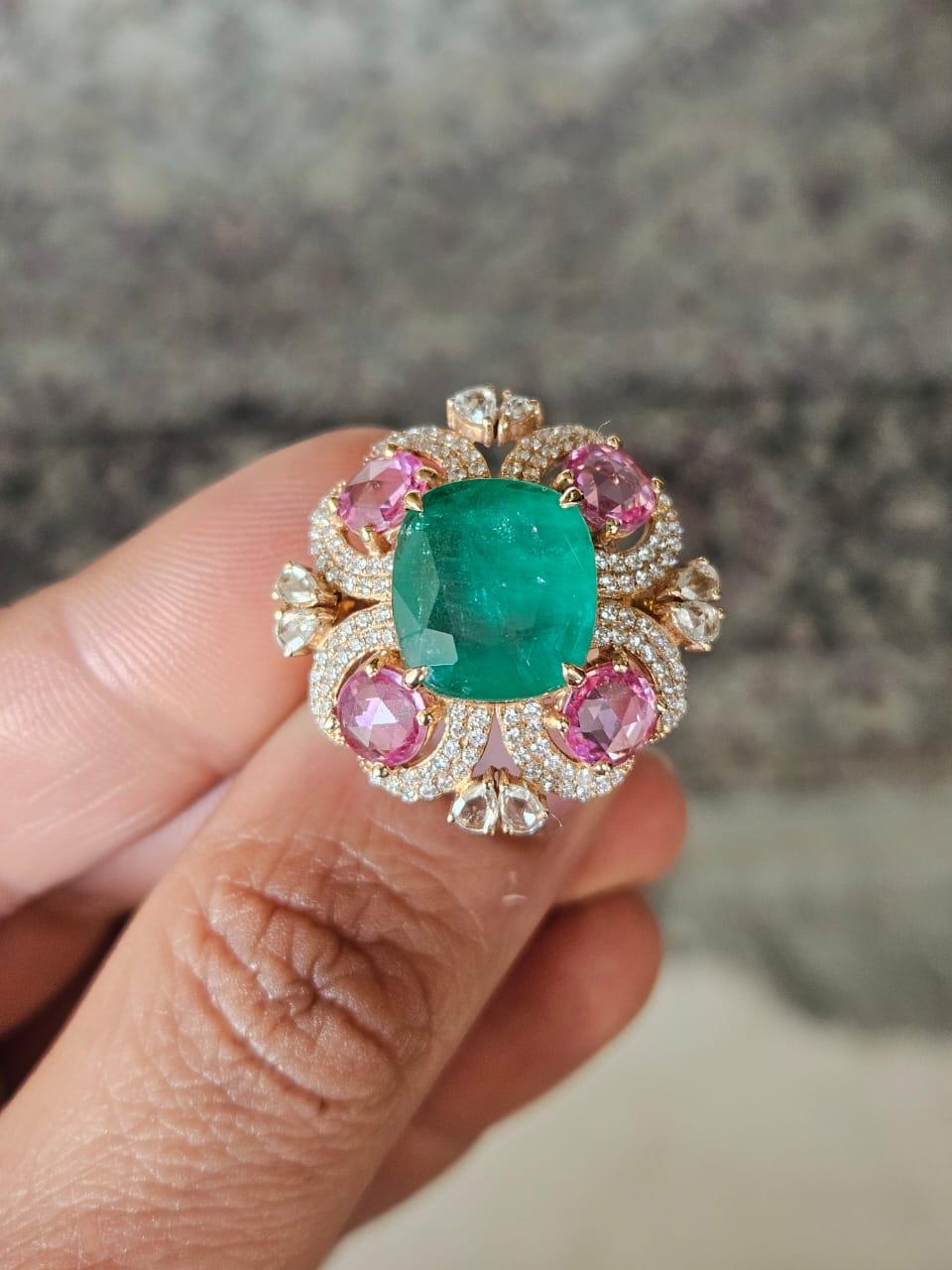 A very gorgeous and beautiful, Emerald & Pink Sapphires Cocktail Ring set in 18K Rose Gold & natural Diamonds. The weight of the Emerald is 7.14 carats. The Emerald is completely natural, without any treatment and is of Zambian origin. The weight of