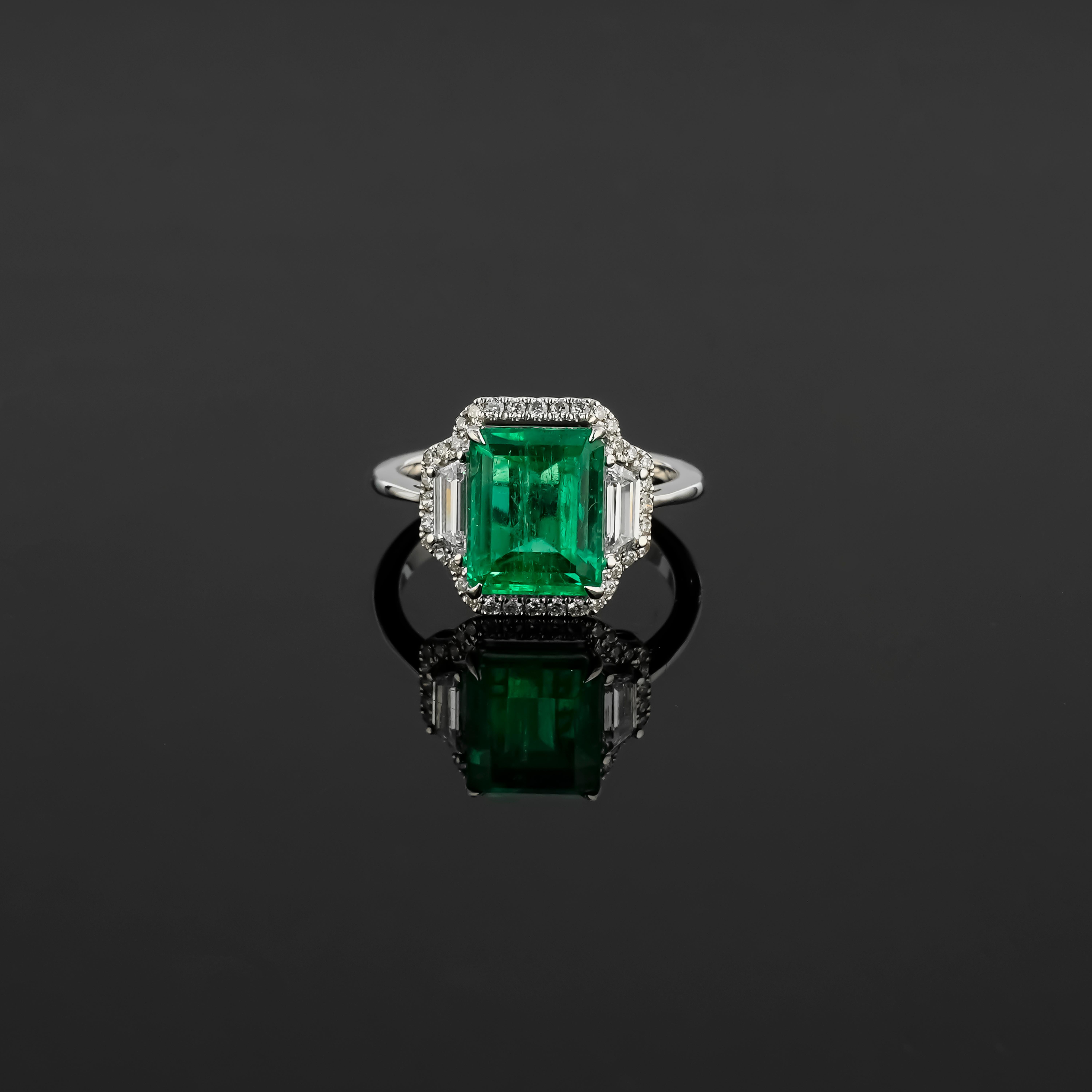 This ring showcases a magnificent 4.27-carat octagonal emerald of Colombian origin, measuring 8.2 x 10.3 mm. The emerald cut highlights the gemstone's rich green color and natural clarity, making it a centerpiece of luxury.

Flanking the emerald are