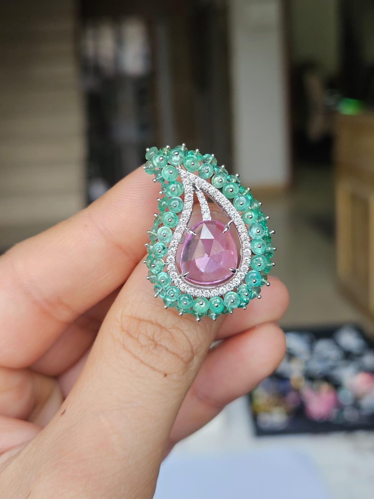 Un anillo de cóctel de Esmeraldas y Zafiro Rosa de estilo moderno, precioso y hermoso, engastado en Oro Blanco de 18 quilates y Diamantes naturales. El peso del zafiro rosa es de 2.75 quilates. El zafiro rosa talla rosa es de origen ceilanés (Sri