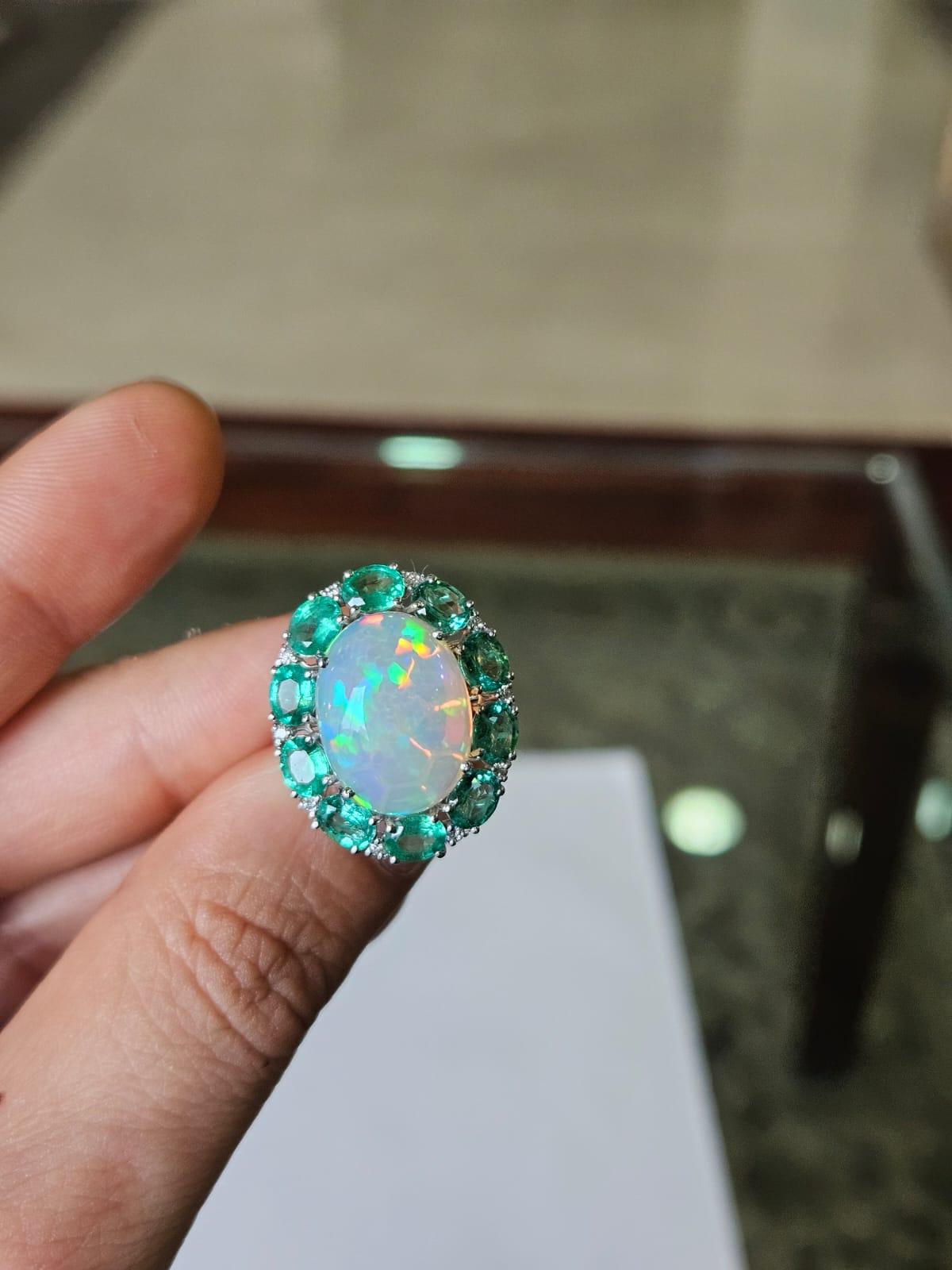 Un bellissimo anello da cocktail con smeraldo e opale in oro bianco 18 carati e diamanti naturali. Il peso dell'opale etiope è di 6.31 carati. Il peso degli smeraldi è di 3,10 carati. Gli smeraldi sono completamente naturali, senza alcun trattamento