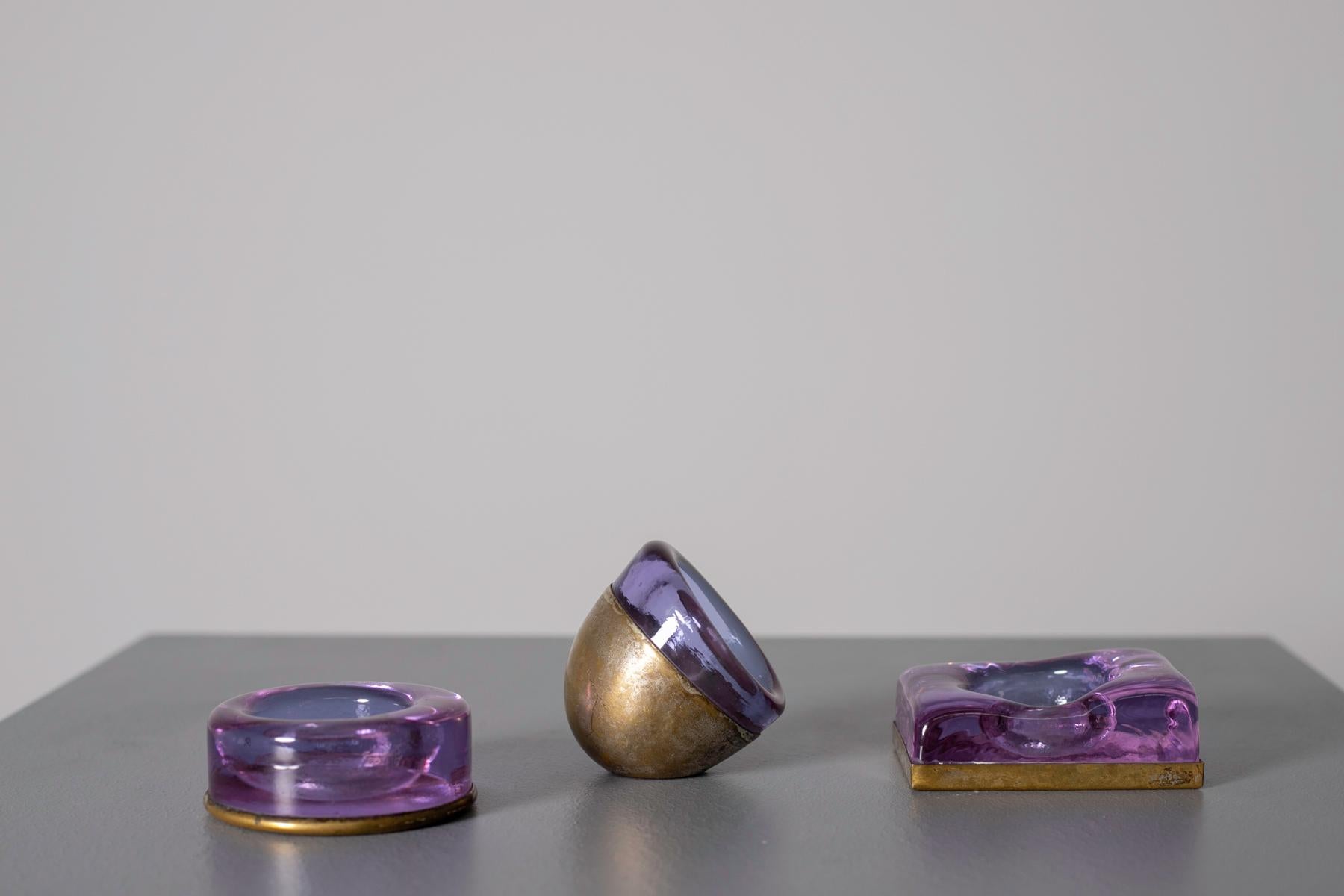 Elegant and sophisticated Italian candle holder set from the 1950s. The set consists of three pieces. Each piece contains a single candle. The candleholder consists of a brass base and is covered with a purple amethyst stone. The purple stone makes