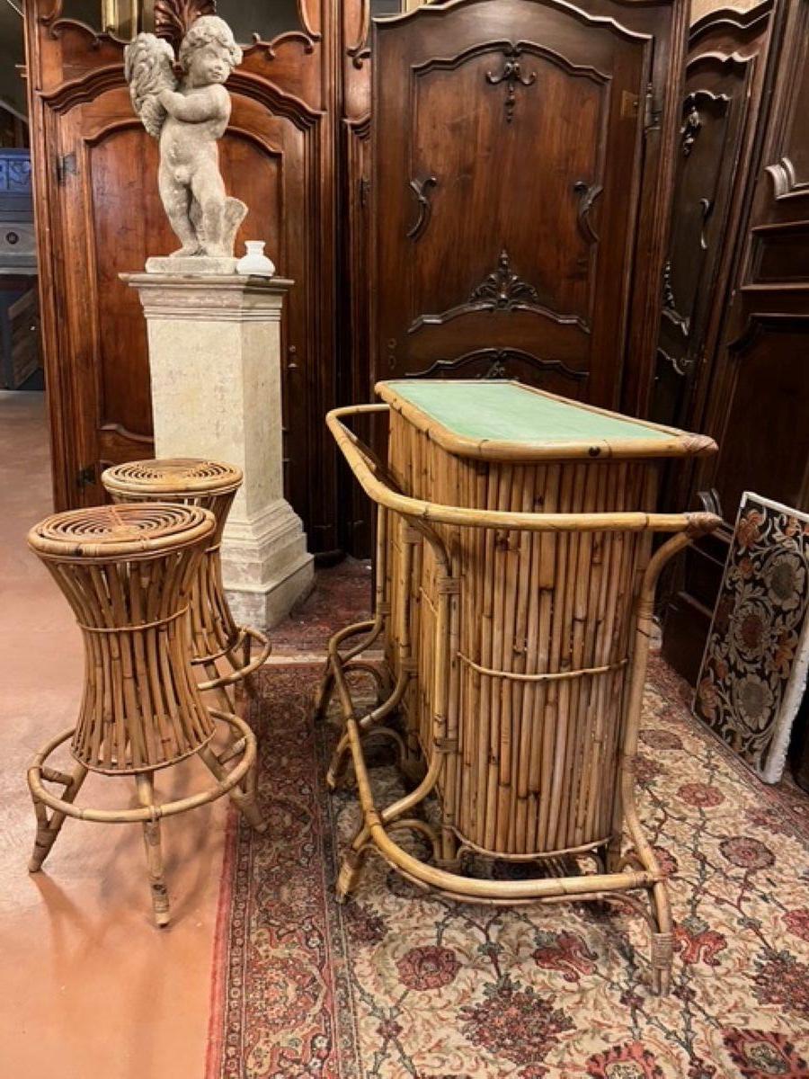 Bellissimo set vintage di mobilio da bar in bamboo, rattan, composto da bancone con ripinai interni, 2 sgabelli alti e 1 mobile portabottiglie rotondo fatto a forma di botte. Annodati e molto belli, ripiani laccati in verde acqua, colore tipico