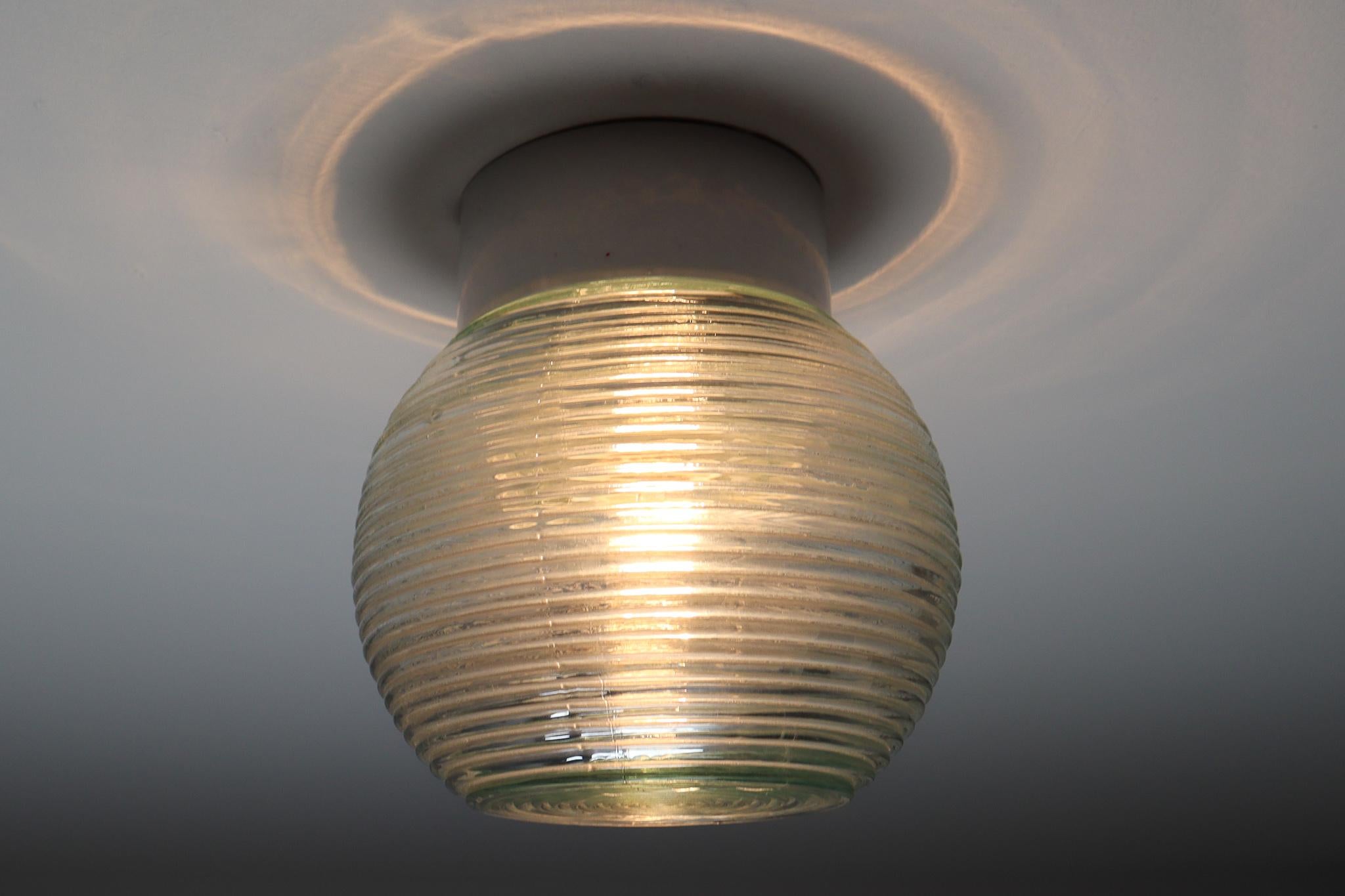 Modern wall/ceiling lights with structured Art-glass and porcelain base, France 1960s. The glass has pattern in it, what gives a nice diffuse light effect and a nice pattern on ceiling and walls, these wall scones/ceiling lights will contribute to a