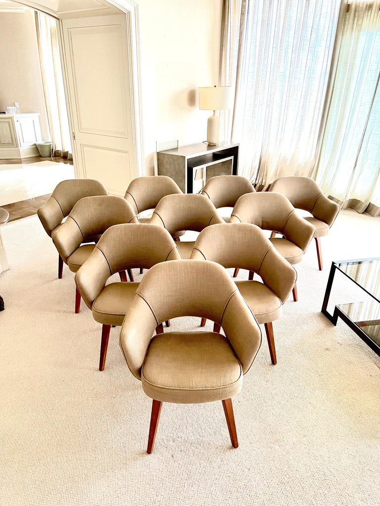 Set of 10 dining Armchairs designed by Eero Saarinen for Knoll. These 10 chairs have been reupholstered in a neutral color and have the original wooden legs. These chairs were made in the 1950's. 10 armchairs. One chair needs minor leg refinishing.