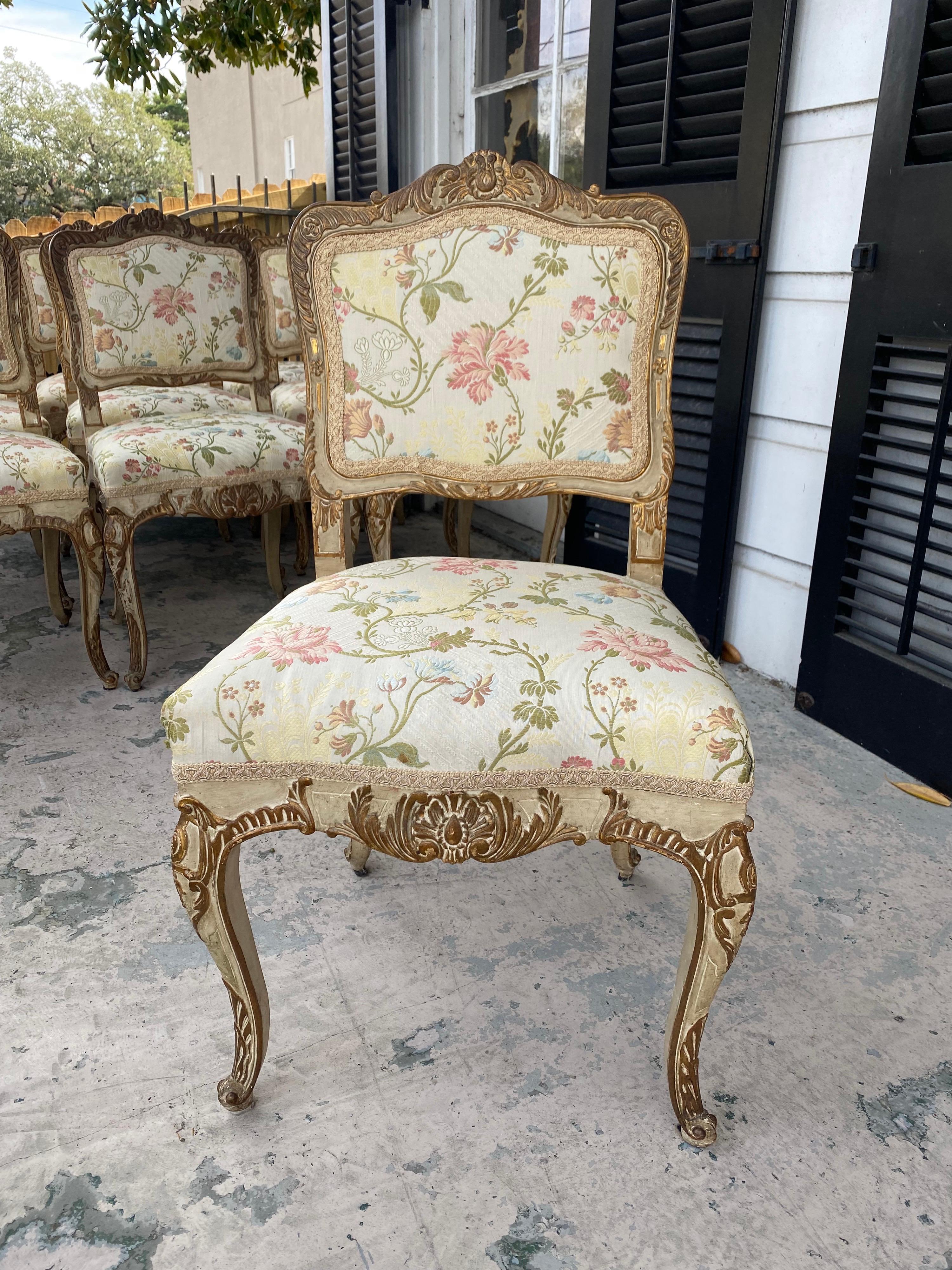 Set of 10 French Regence style 19th c. dining chairs. Painted and parcel gilt finish worn as expected for age. Upholstered in lyonnaise silk that’s in excellent condition.
