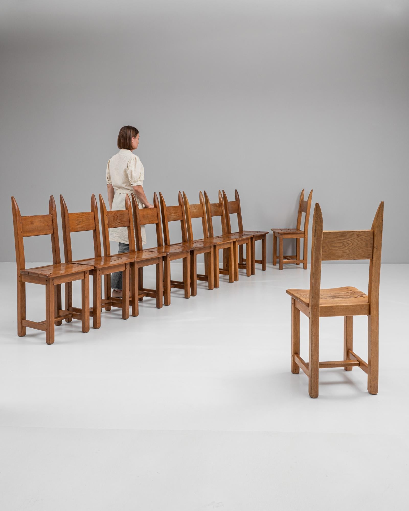 This set of ten vintage dining chairs, crafted in France, embodies the rustic charm and classic craftsmanship of mid-20th-century design. Made from solid wood, each chair showcases a sturdy construction and a warm, natural finish that highlights the
