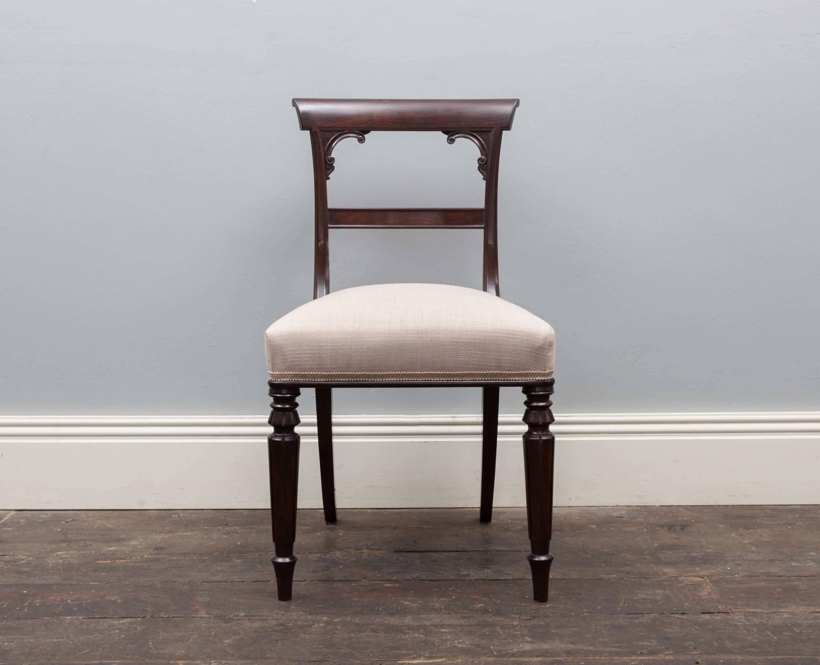 A set of ten elegant antique rosewood dining chairs. Produced during the Regency period, the chairs feature tapering turned legs, bar backs with scroll corners and neutral fabric coverings.
Beautifully made from the finest rosewood, deep and rich