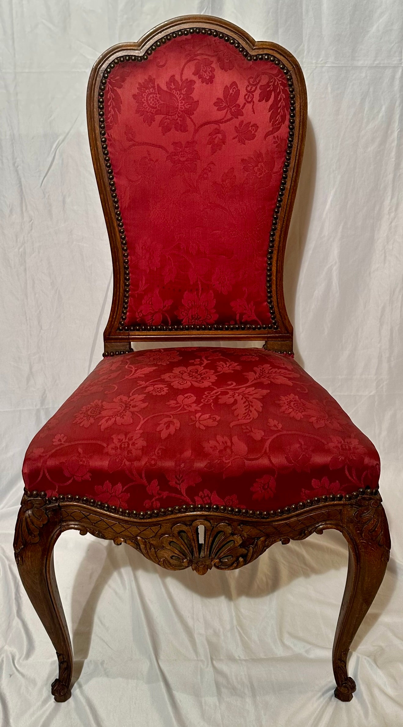 Ensemble de 10 chaises de salle à manger anciennes en noyer finement sculpté et tapisserie en soie rouge avec détails d'œillets, vers 1880.