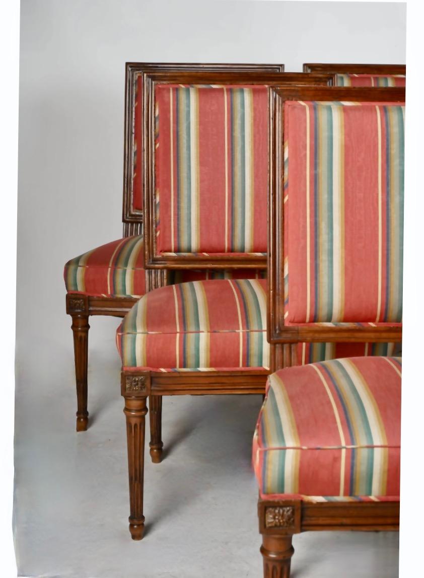 This is a superb set of classic antique-early 20th century-Louis XVI-style-dining chairs. These solid walnut chairs are in remarkably good solid condition while retaining their original wood surface. The chairs were reupholstered in a striped