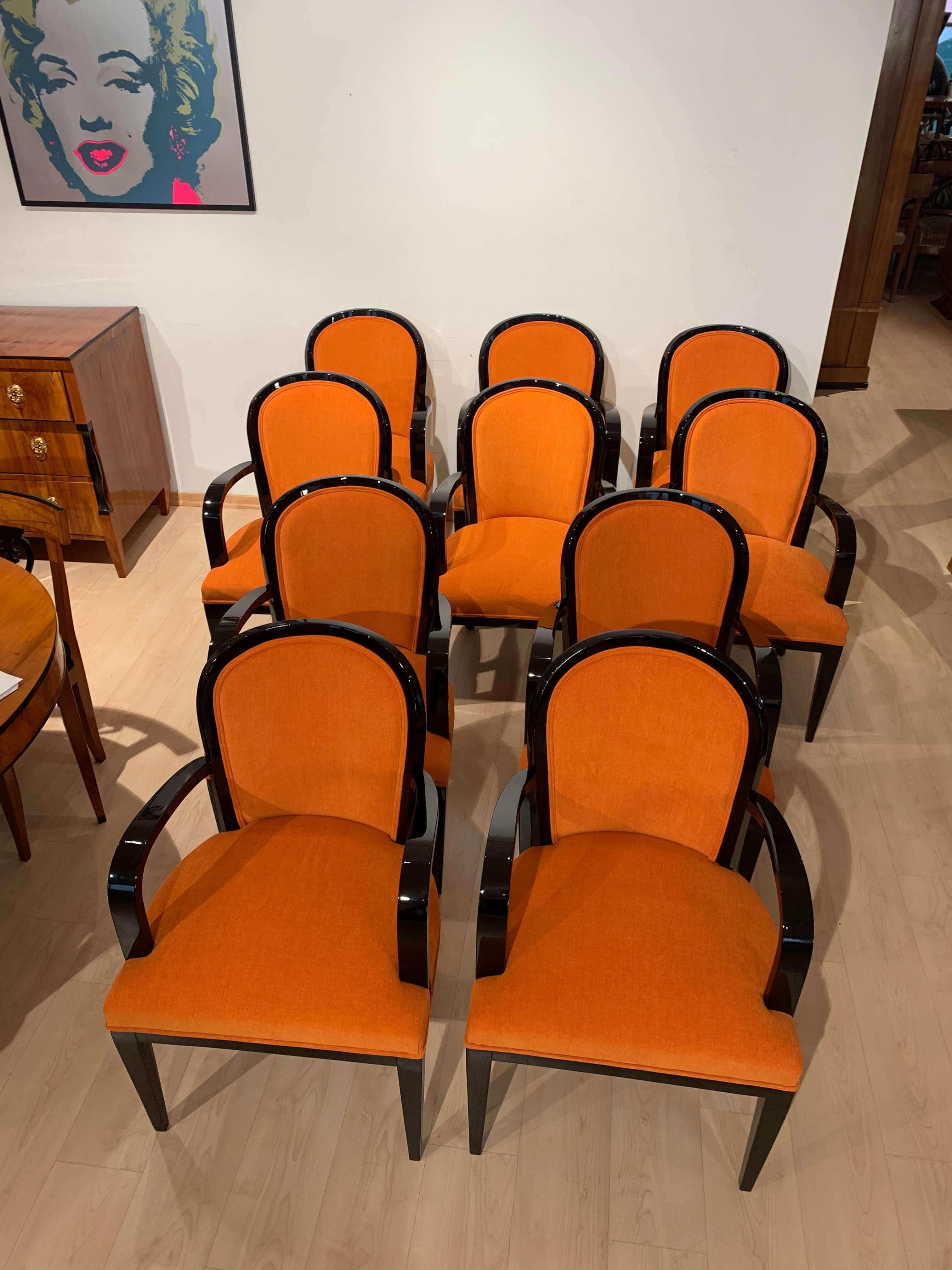 Exquisite set of ten original Art Deco Dining Chairs from France, circa 1930. These elegant armchairs feature a classic Art Deco design with a curved backrest and open armrests, crafted from solid beech wood and finished with a black piano lacquer