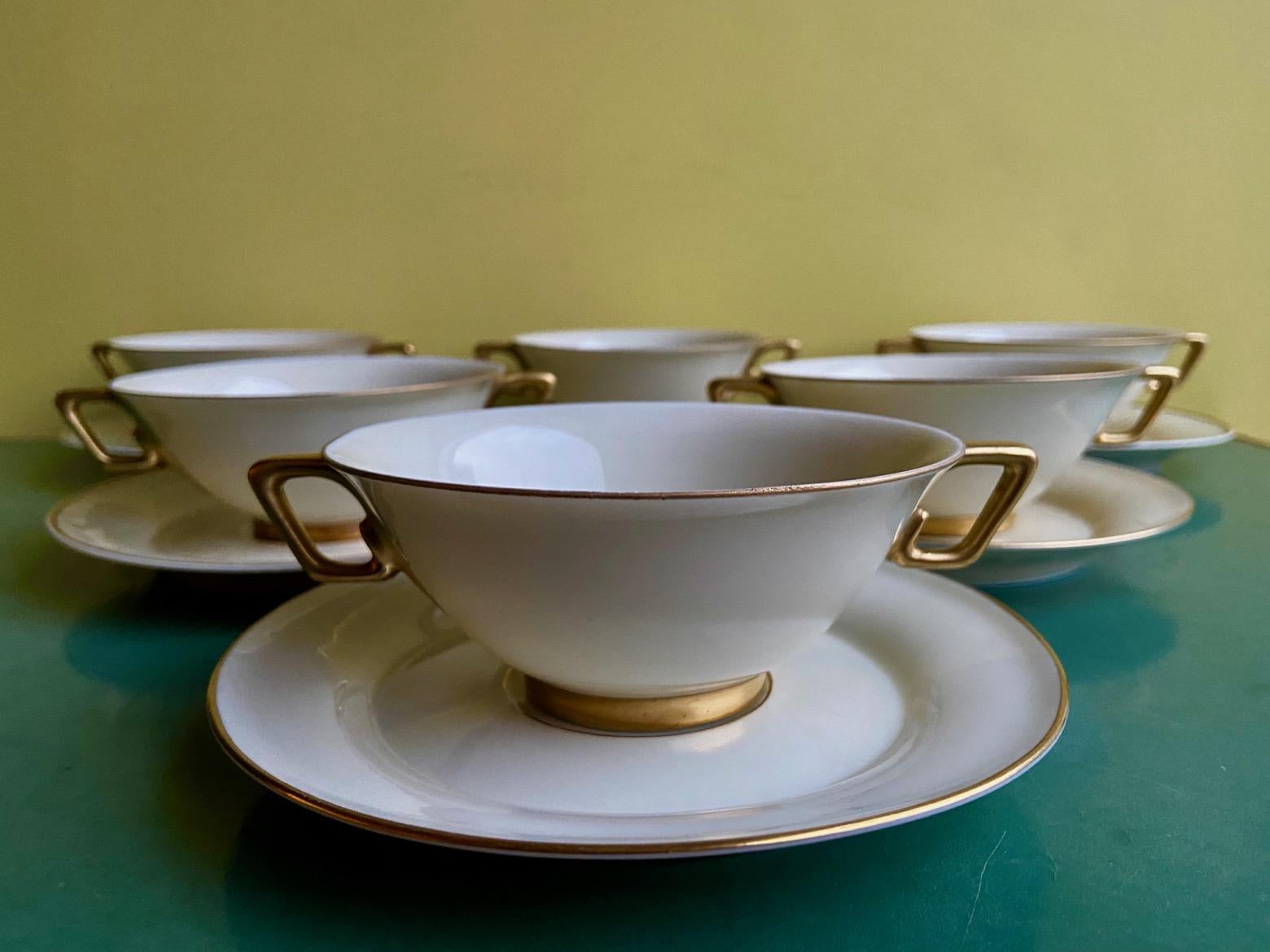 A Rare and Stylish Gold Rimmed Ivory White Art Deco Limoges Porcelain Cream, consomme or Soup set for 10 by Marcel Goupy for Rouaud Paris. 
Antique Ivory white with hand painted gold decoration and signature. 
Dimensions 
Soup bowl 14.5cm 11cm x