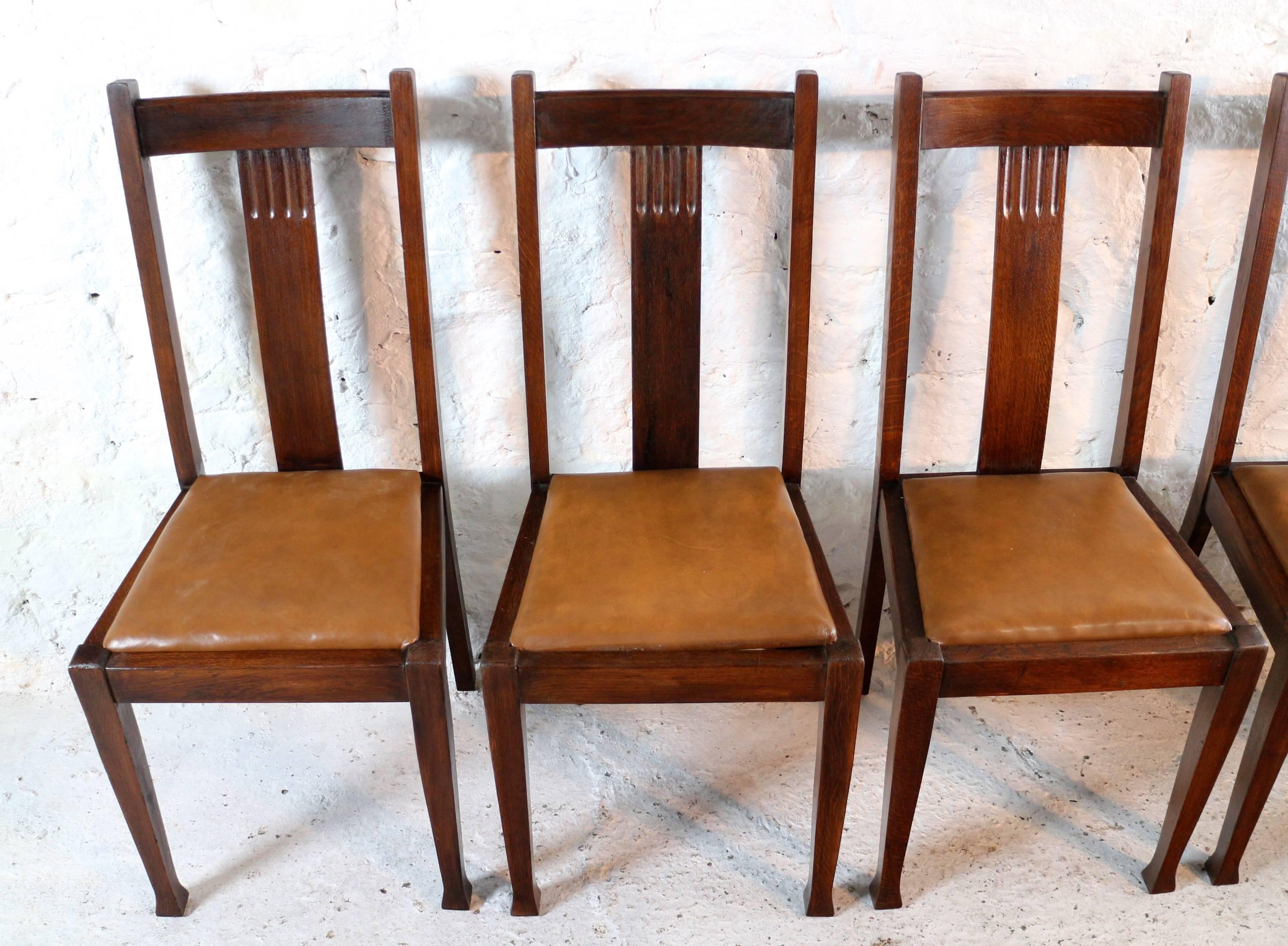 A nice set of ten Arts & Crafts dining chairs similar to the American Mission style but with shaped tapering legs. With a curved top rail and wide centre splat with fluting they have tan leather covered drop-in seat pads and slightly outplayed