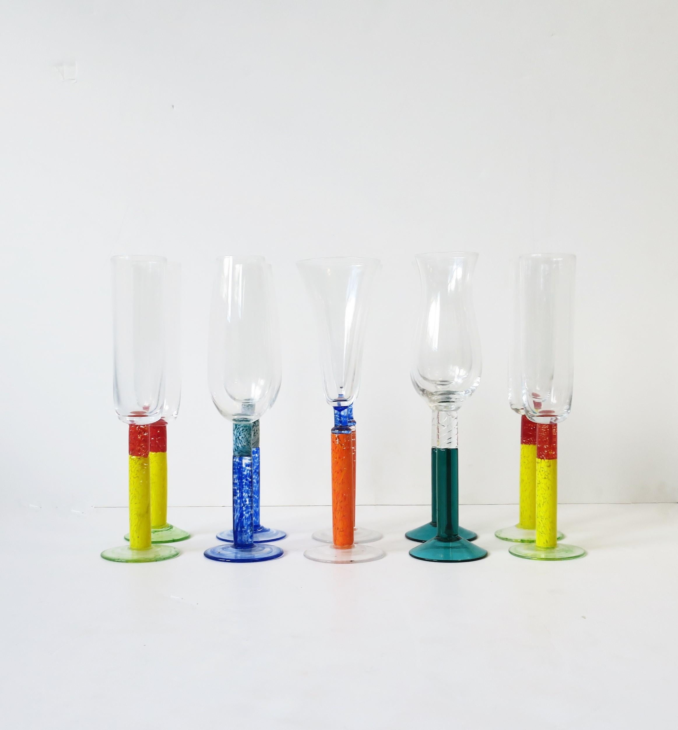 A beautiful set of ten (10) colorful art glass Champagne flute glasses, circa 1990s, Europe. In the style of Kosta Boda, Sweden. Colors include: Red, yellow, orange, blue, teal blue/blue-green. A beautiful set for home, summer, holiday entertaining