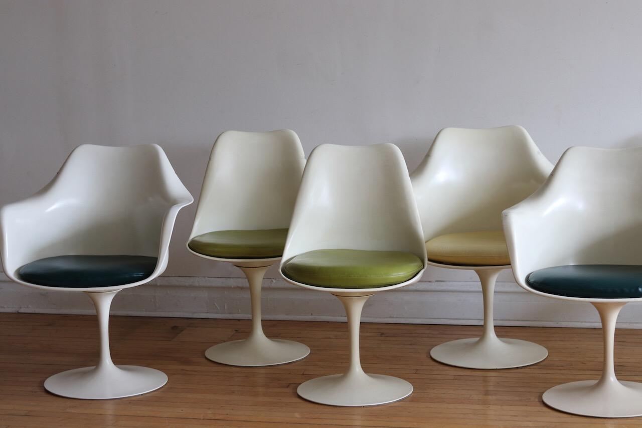 Set of ten Mid-Century Modern white tulip swivel dining chairs. 
Designed by Eero Saarinen for Knoll International. 
Various vinyl upholstery fabrics made by Knoll.
Four lime green and two beige seat cushions are the original vinyl