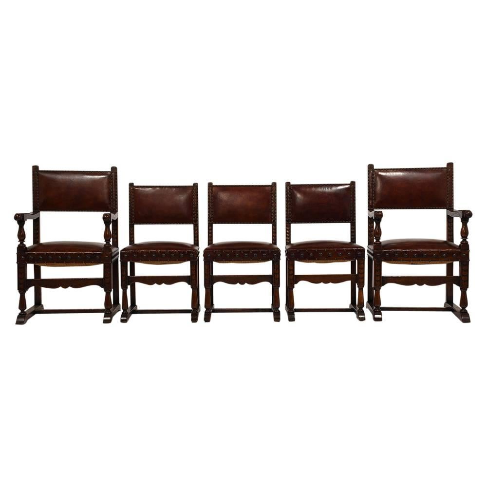 This set of ten 1900s Antique Baroque-style dining chairs feature solid oak wood frames with the original dark walnut color finish. The frames are adorned with carved accents and turned wood arms and legs. The chair seat and back are upholstered in