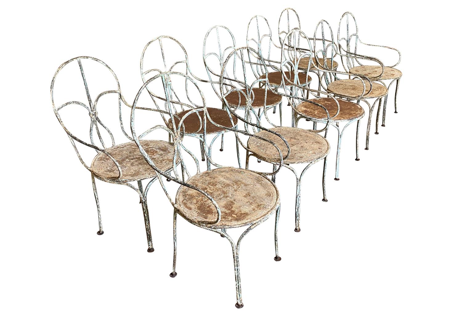 A tremendous set of 10 garden dining chairs from the Provence region of France. Soundly constructed from painted iron. Great patina. The seat height is 17