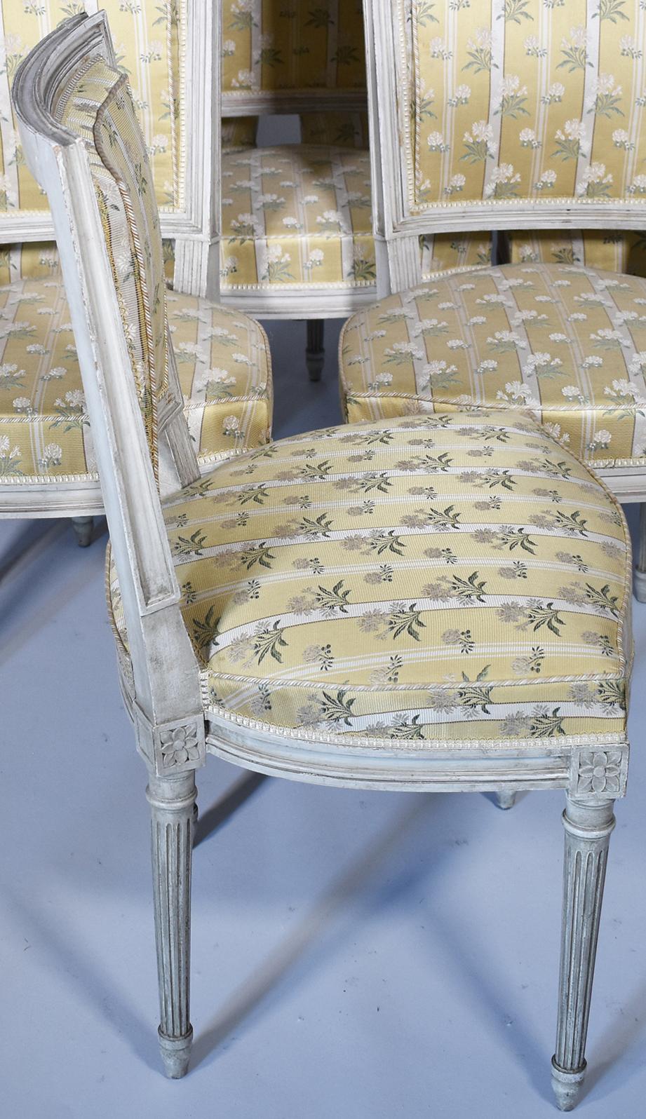 Elegant Louis XVI framed back chairs, featuring pale white patina. Look charming when juxtaposed to modern table or period dining table. Fluted carving on legs and rosettes in corners add detail to the neoclassical style. Reupholstered in black