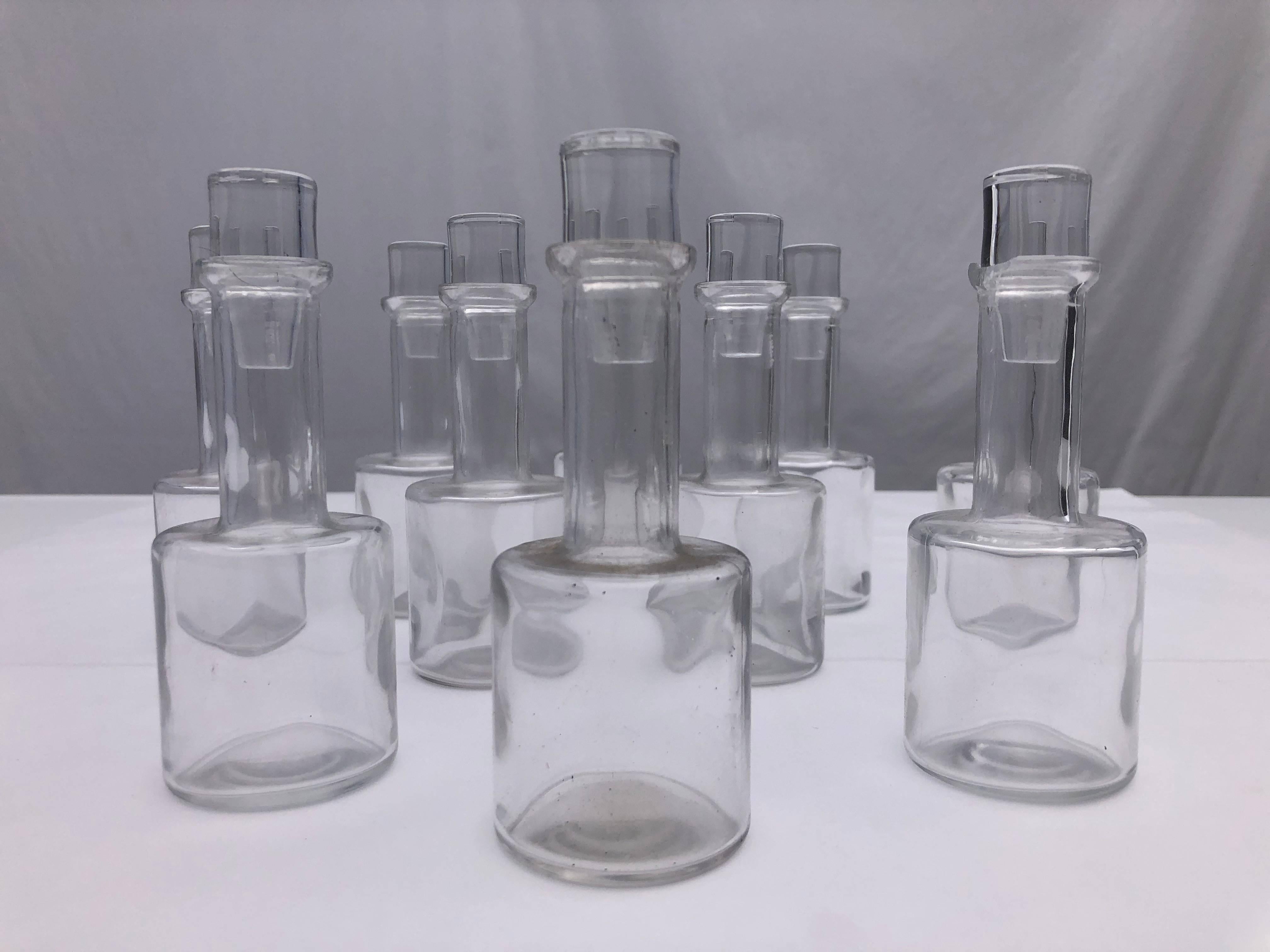 This is a set of 10 hand blown glass bottles with stoppers that came from a Parisian restaurant. The stoppers have frosted glass and together the bottles and stoppers make a lovely collection. They could be used in a kitchen to hold oils and spices