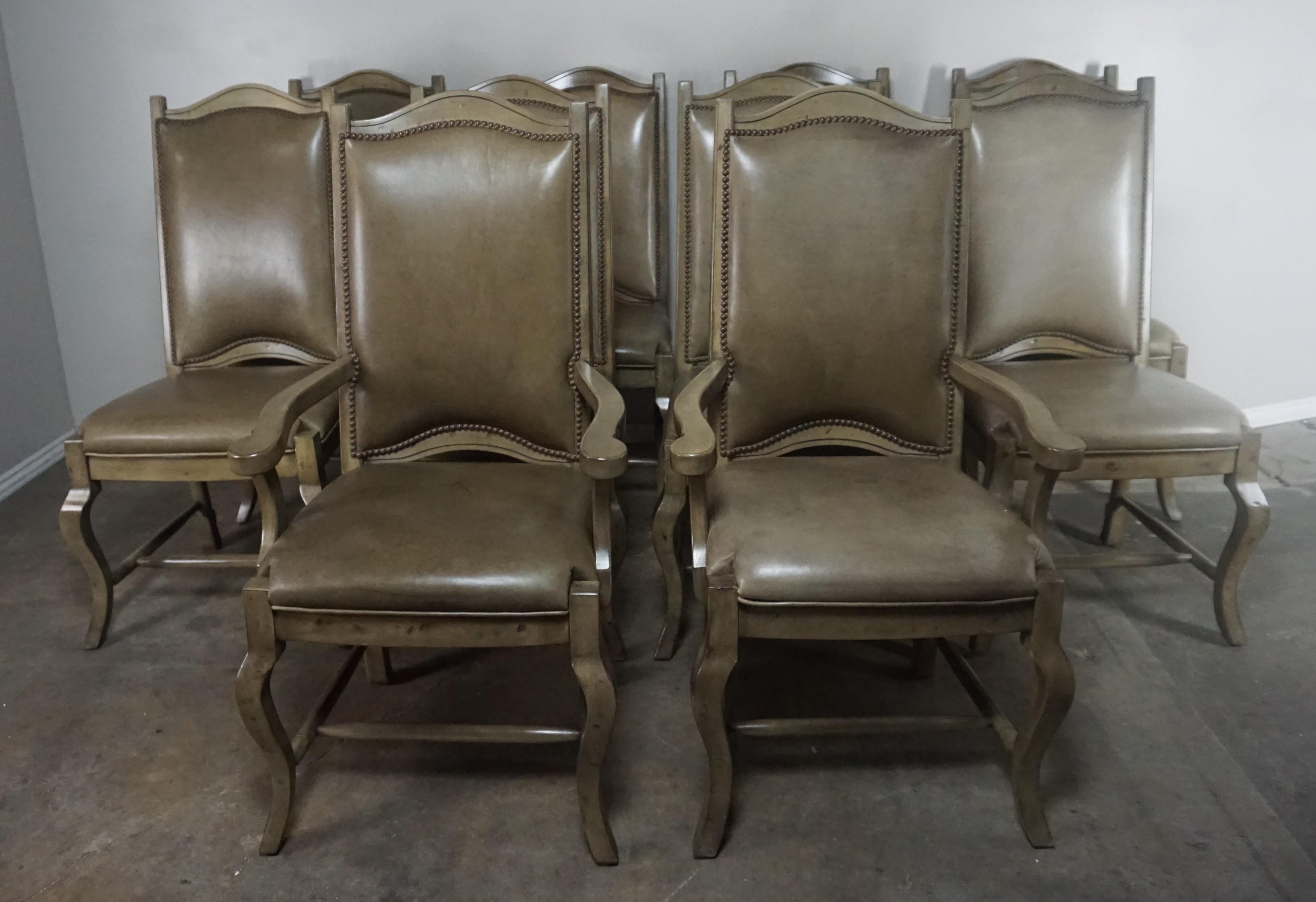Set of ten Country French style leather upholstered ladder back dining chairs. Upholstered in a soft taupe colored cow hide with nailhead trim detail.
Measures: Armchairs 25 x 25 x 46
Side chairs 23.5 x 25 x 46
Seat height 20.5 on all.
 